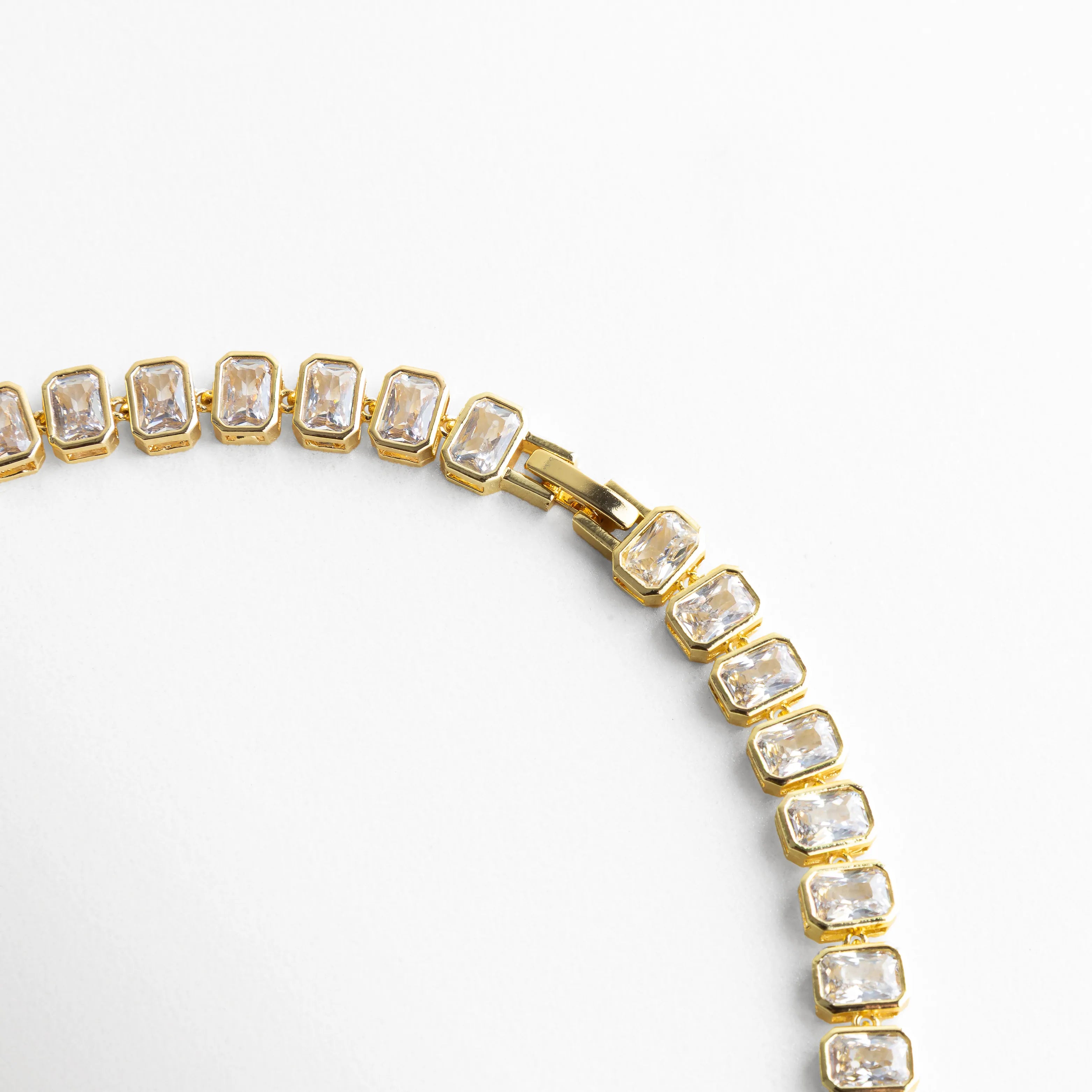 Detalle lateral de collar Jung Golden con zirconias cúbicas en fila continua, Segmento de collar dorado con piedras cuadradas perfectamente alineadas, Vista cercana de collar elegante con acabado oro 18K y brillo uniforme, Collar tipo tenis con zirconias mostrando estructura y diseño premium, Detalle fino de joyería dorada con piedras brillantes de corte cuadrado