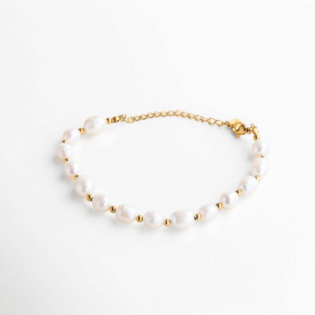 pulsera dorada con perlas de agua de imitación, diseño elegante y atemporal, acabado en oro 18K, joya femenina y sofisticada, pieza ideal para combinar con otros accesorios