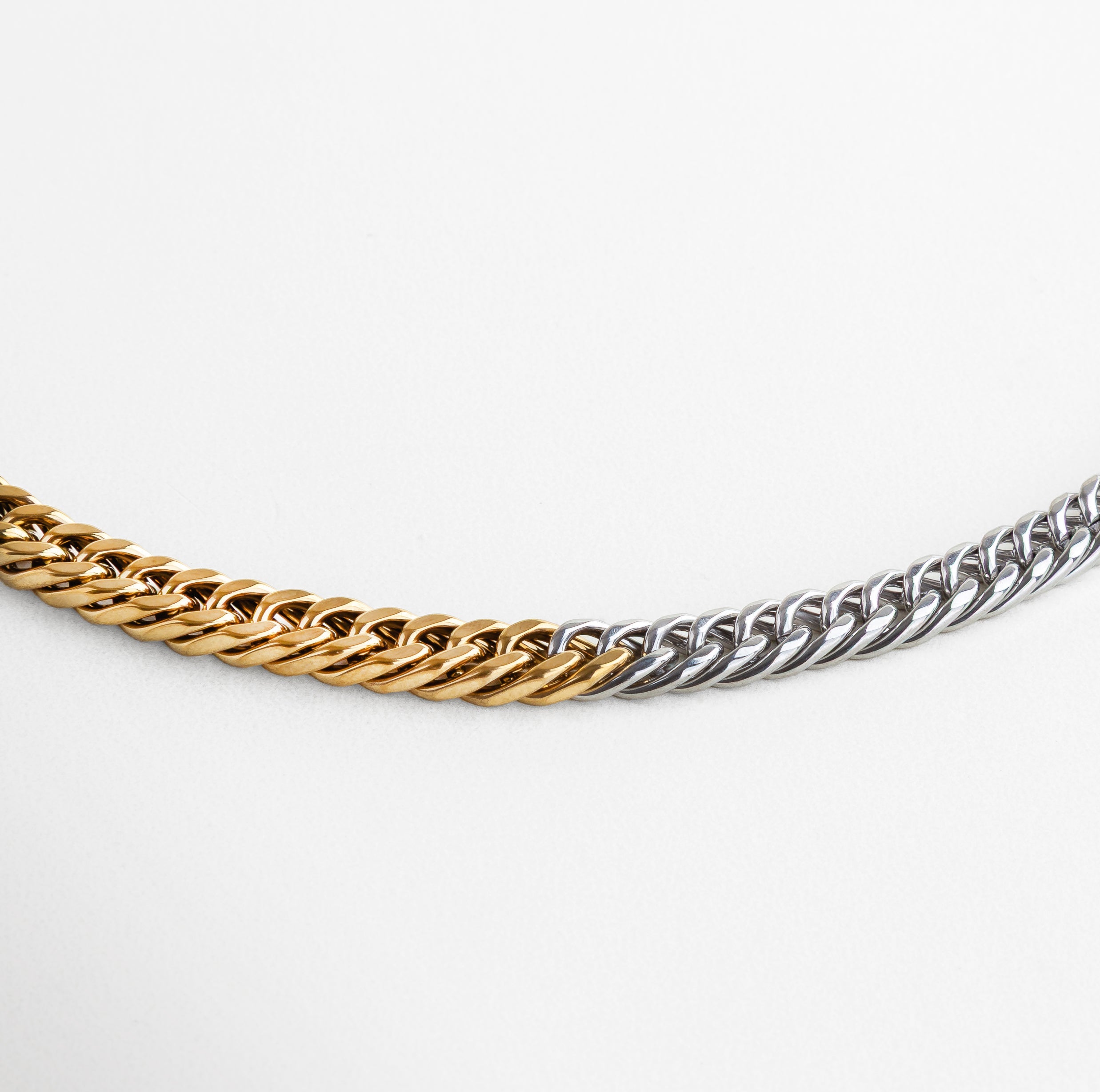 Detalle del contraste entre acero plateado y chapa de oro 18K, Acercamiento a los eslabones con acabado bicolor, Textura metálica con recubrimiento parcial dorado, Diseño en acero con secciones doradas integradas