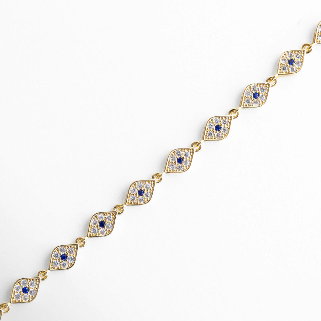Detalle de pulsera dorada con ojo turco y zirconias incrustadas en acabado brillante, Primer plano de pulsera en chapa de oro 18K con diseño de ojos turcos y piedras zirconia, Vista lateral de pulsera elegante con eslabones dorados y detalles místicos de ojo turco, Acercamiento a pulsera con zirconias brillantes y diseño simbólico de protección, Detalle fino de pulsera dorada con acabado pulido y pequeñas incrustaciones de zirconia