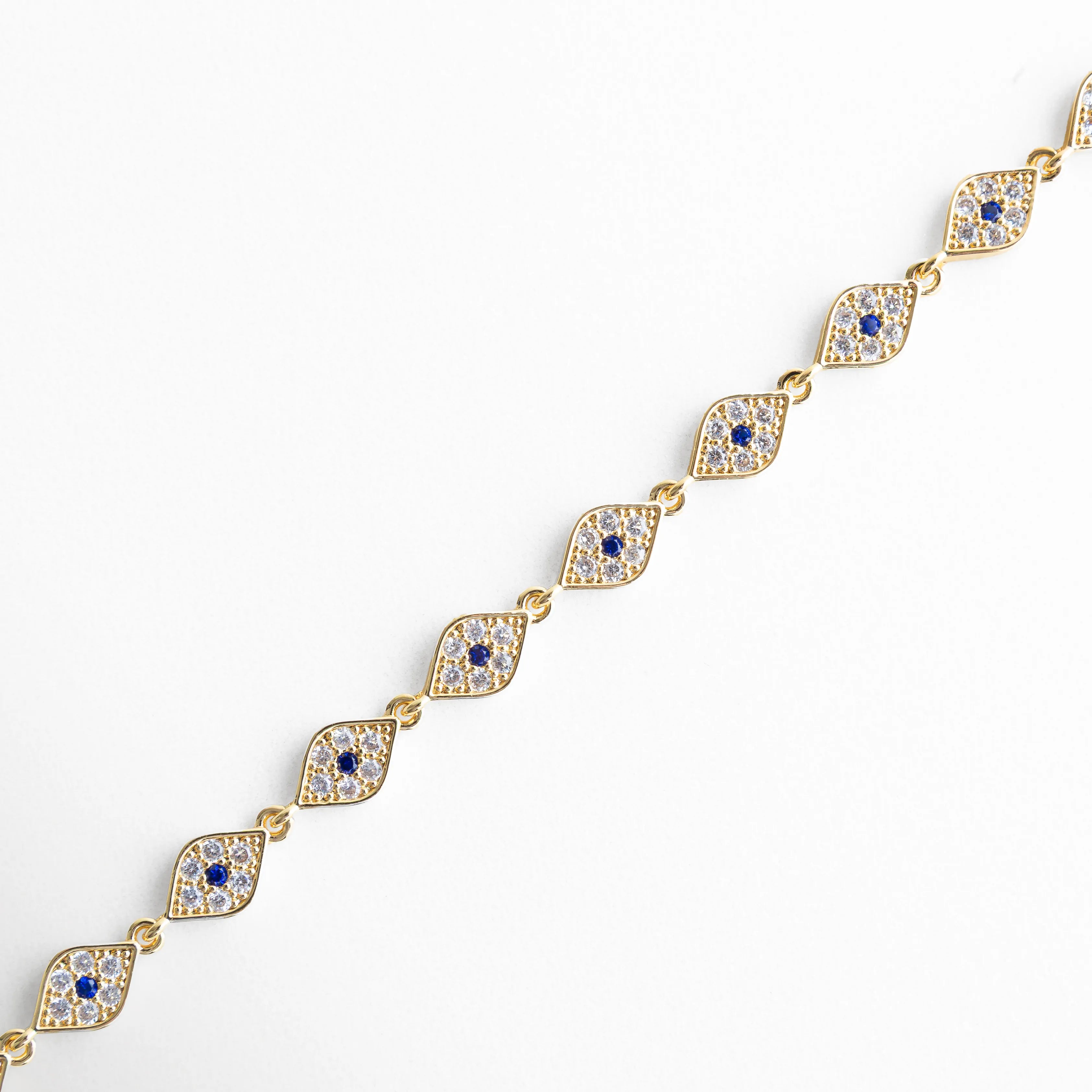 Detalle de pulsera dorada con ojo turco y zirconias incrustadas en acabado brillante, Primer plano de pulsera en chapa de oro 18K con diseño de ojos turcos y piedras zirconia, Vista lateral de pulsera elegante con eslabones dorados y detalles místicos de ojo turco, Acercamiento a pulsera con zirconias brillantes y diseño simbólico de protección, Detalle fino de pulsera dorada con acabado pulido y pequeñas incrustaciones de zirconia