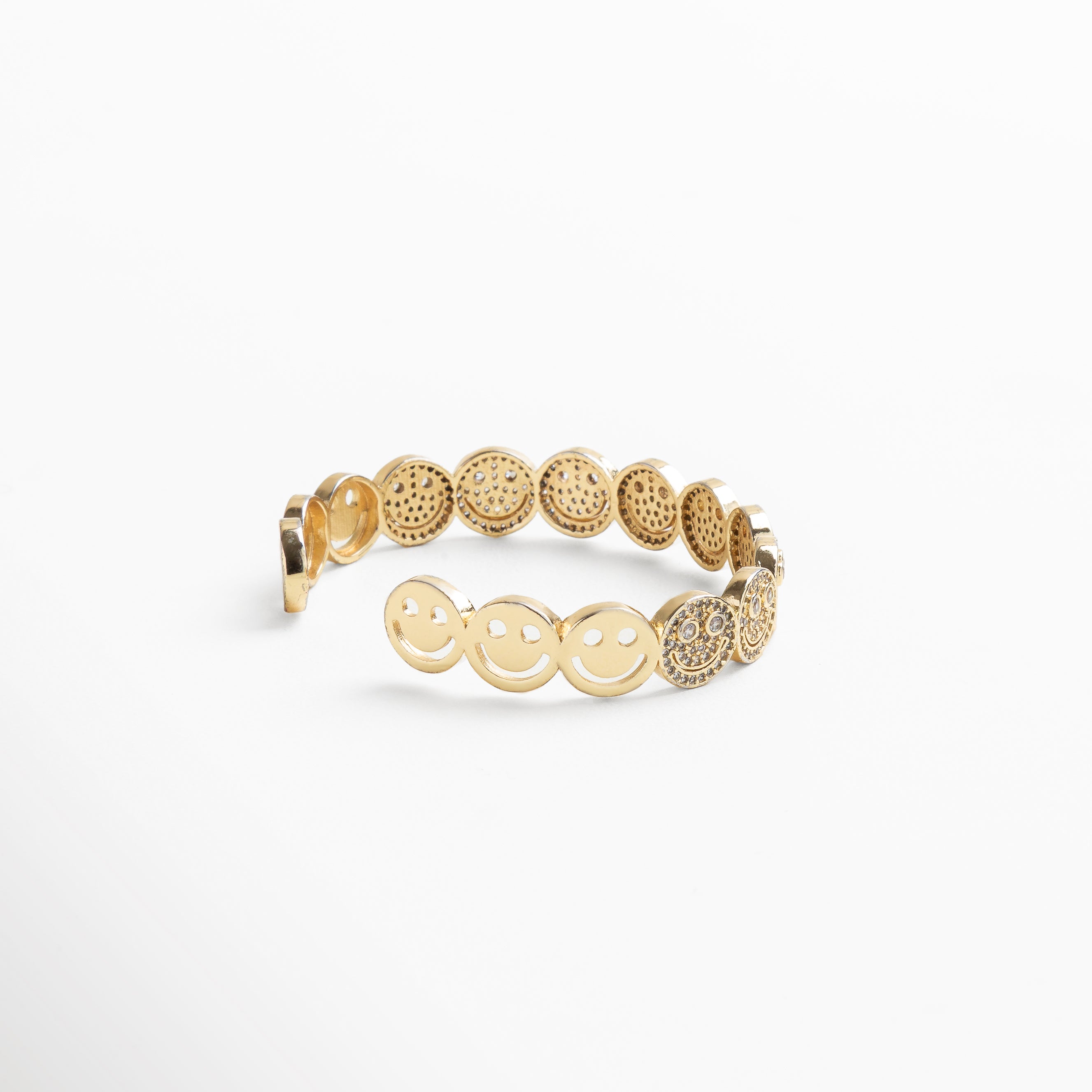 detalle de caritas sonrientes con zirconias en dorado, primeros planos de las caritas brillantes incrustadas, acabado texturizado de las caritas en la pulsera dorada, zirconias cúbicas sobre diseño de caritas en pulsera, caritas con brillo sutil sobre base enchapada en oro 