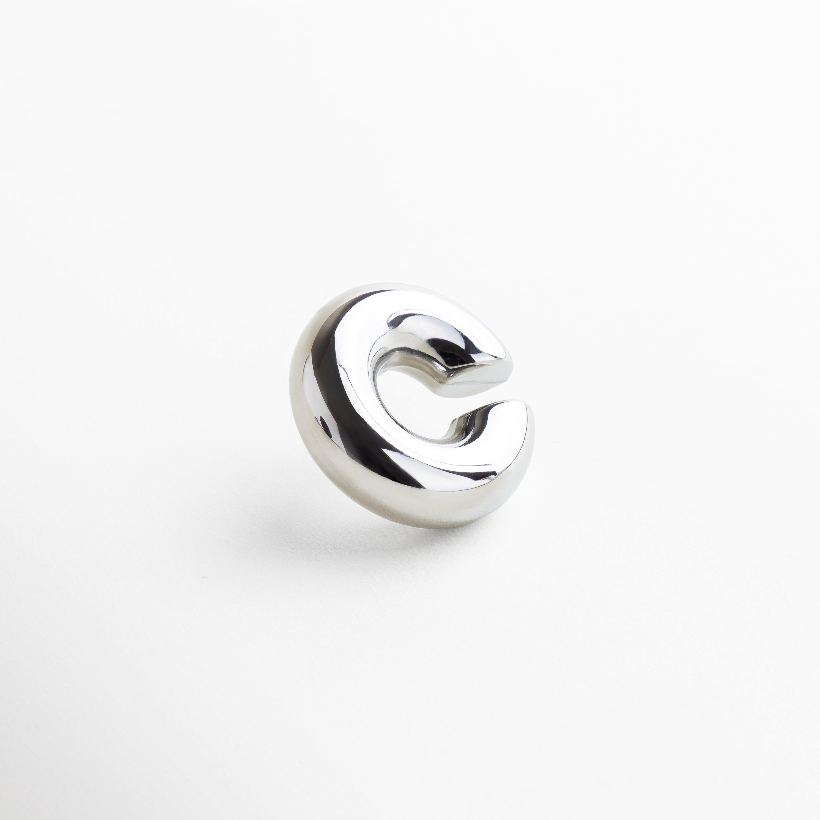Ear cuff plateado con diseño moderno y minimalista, Accesorio para oreja en acero inoxidable con baño plateado, Ear cuff elegante en acero inoxidable acabado pulido, Pieza statement plateada para oreja, tendencia actual
