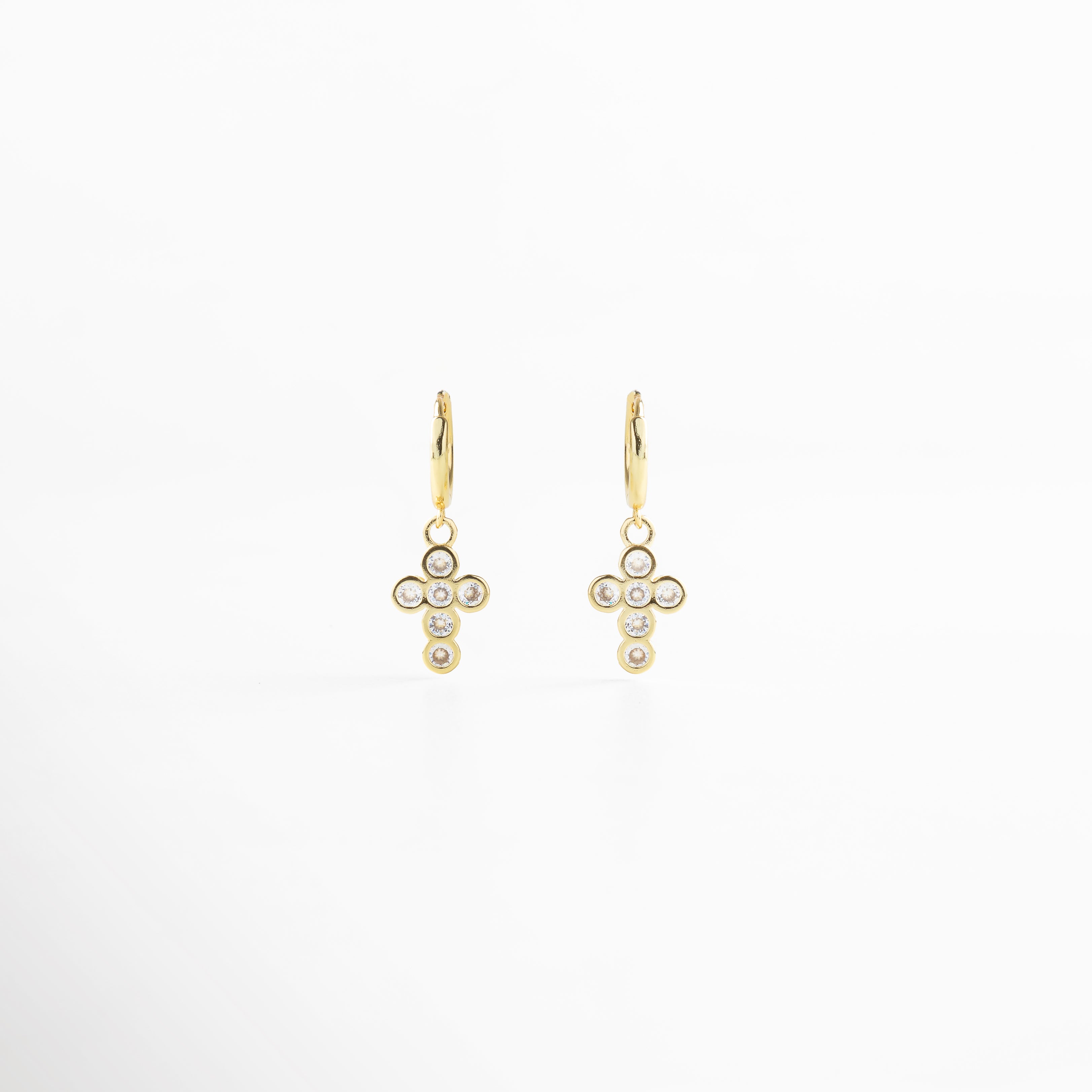 Aretes de cruz dorada vistos de frente, con pequeñas zirconias incrustadas que capturan la luz. Vista frontal de los aretes con diseño de cruz brillante, estilo elegante y atemporal. Aretes dorados con zirconias en forma de cruz, fotografía frontal completa sobre fondo neutro. Primer plano frontal de aretes de cruz dorada, destacando su brillo delicado.Par de aretes dorados en forma de cruz con detalles brillantes, vistos de frente.
