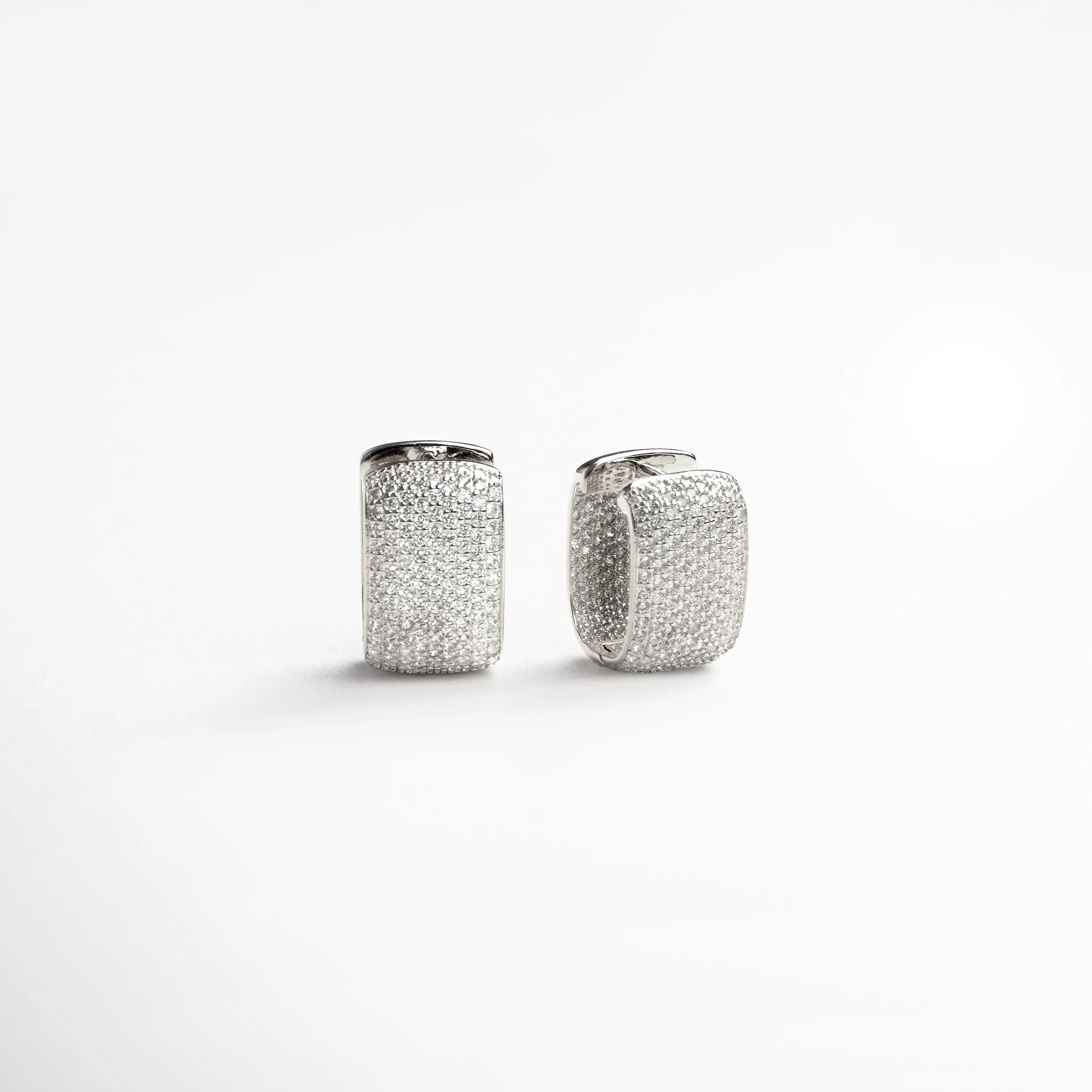 aretes plateados brillantes, aretes tipo huggie, joyería plateada elegante, aretes con textura, accesorios plateados modernos, aretes sofisticados mujer, joyería chic plateada, aretes compactos