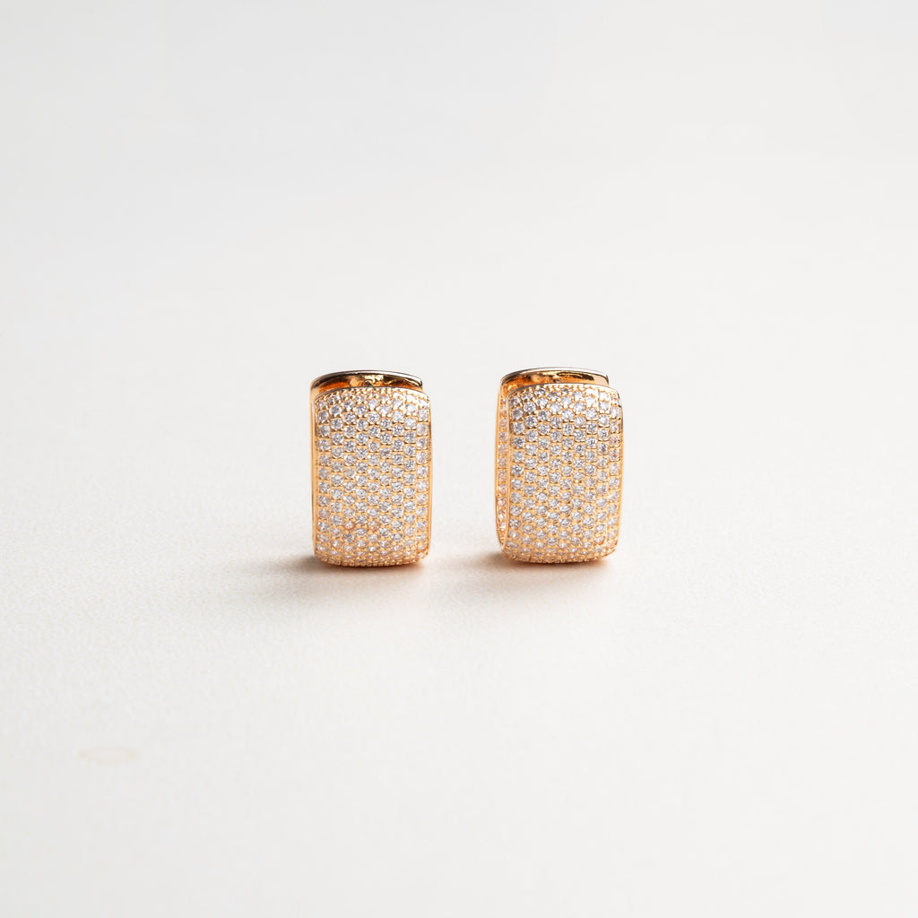 Elegantes aretes con zirconias medianamente grandes, brillando intensamente en un diseño sofisticado, ideal para ocasiones especiales y para dar un toque de lujo y estilo a cualquier look.