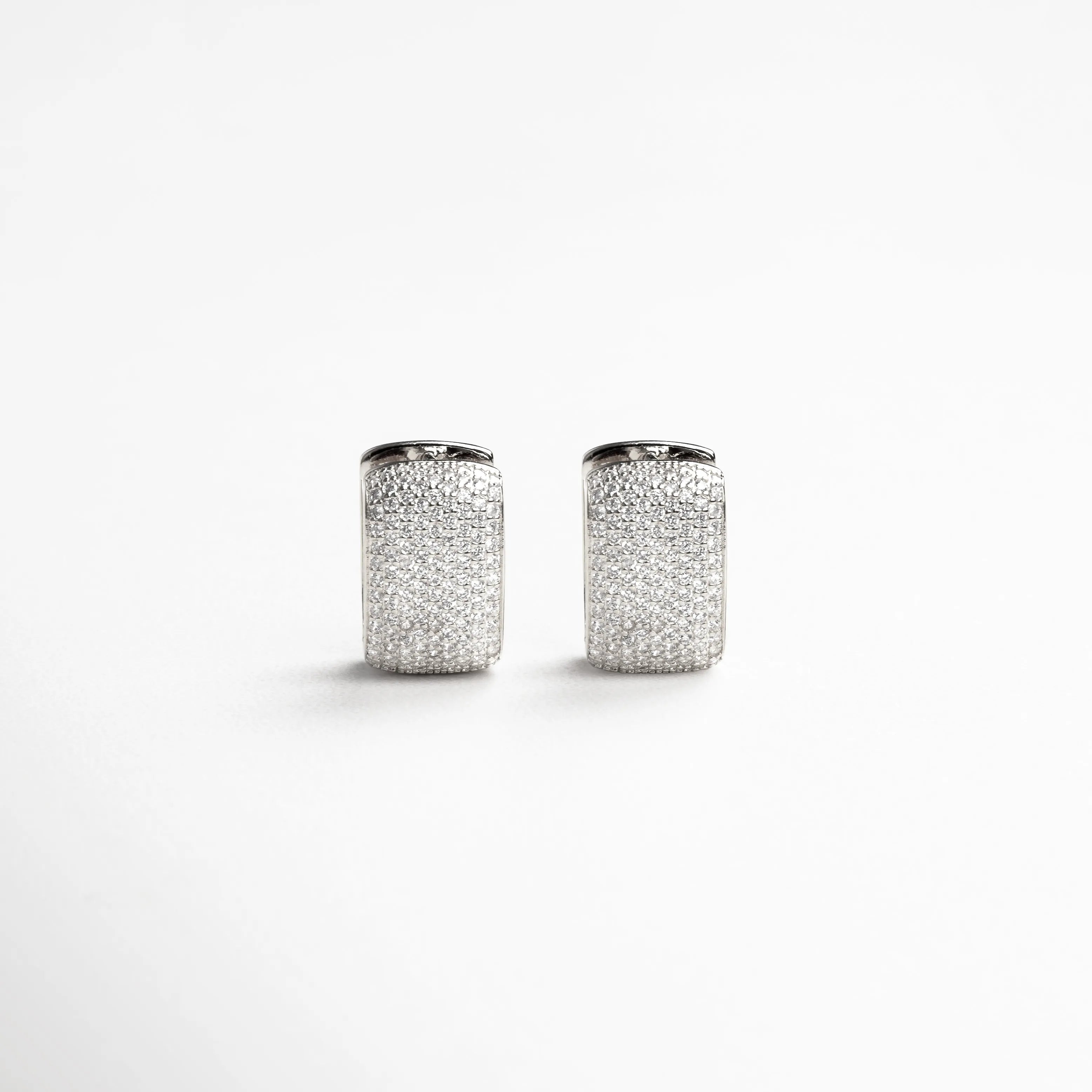 aretes plateados vista frontal, aretes pequeños elegantes, joyería plateada moderna, accesorios femeninos plateados, aretes brillantes chic, joyería minimal luminosa, aretes contemporáneos, aretes refinados