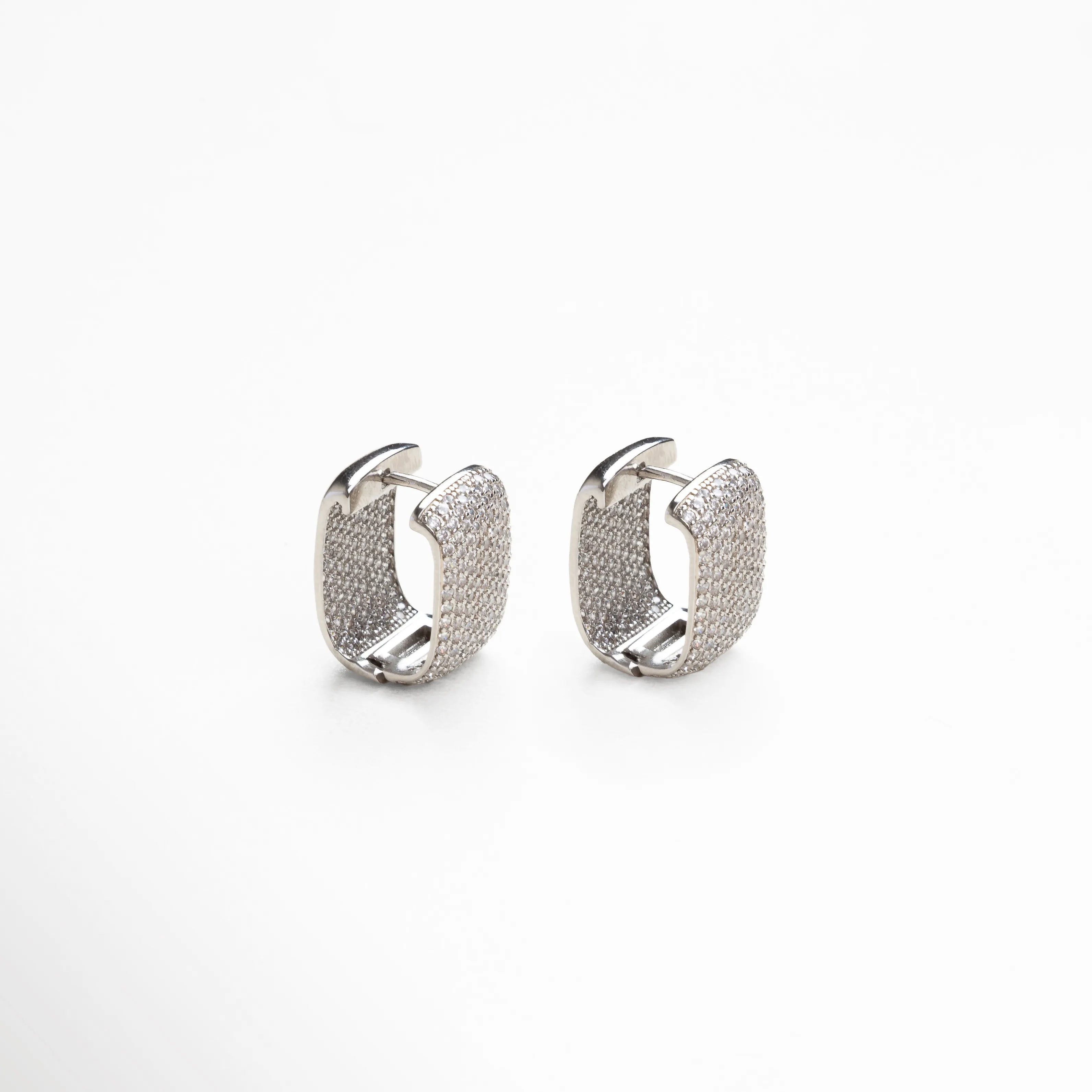 aretes plateados vista lateral, detalle broche aretes, joyería plateada contemporánea, aretes tipo aro pequeño, accesorios plateados sofisticados, aretes con diseño pulido, joyería femenina moderna, aretes chic plateados