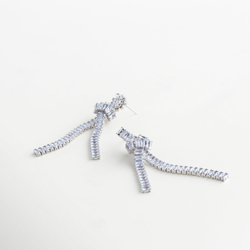 Aretes largos plateados usados, con caída de cadenas y zirconias, Aretes Noir Knot plateados con nudo metálico y toque sofisticado, Joyería plateada moderna con brillo sutil y diseño escultural, Aretes femeninos con caída de 8.7 cm y acabado brillante