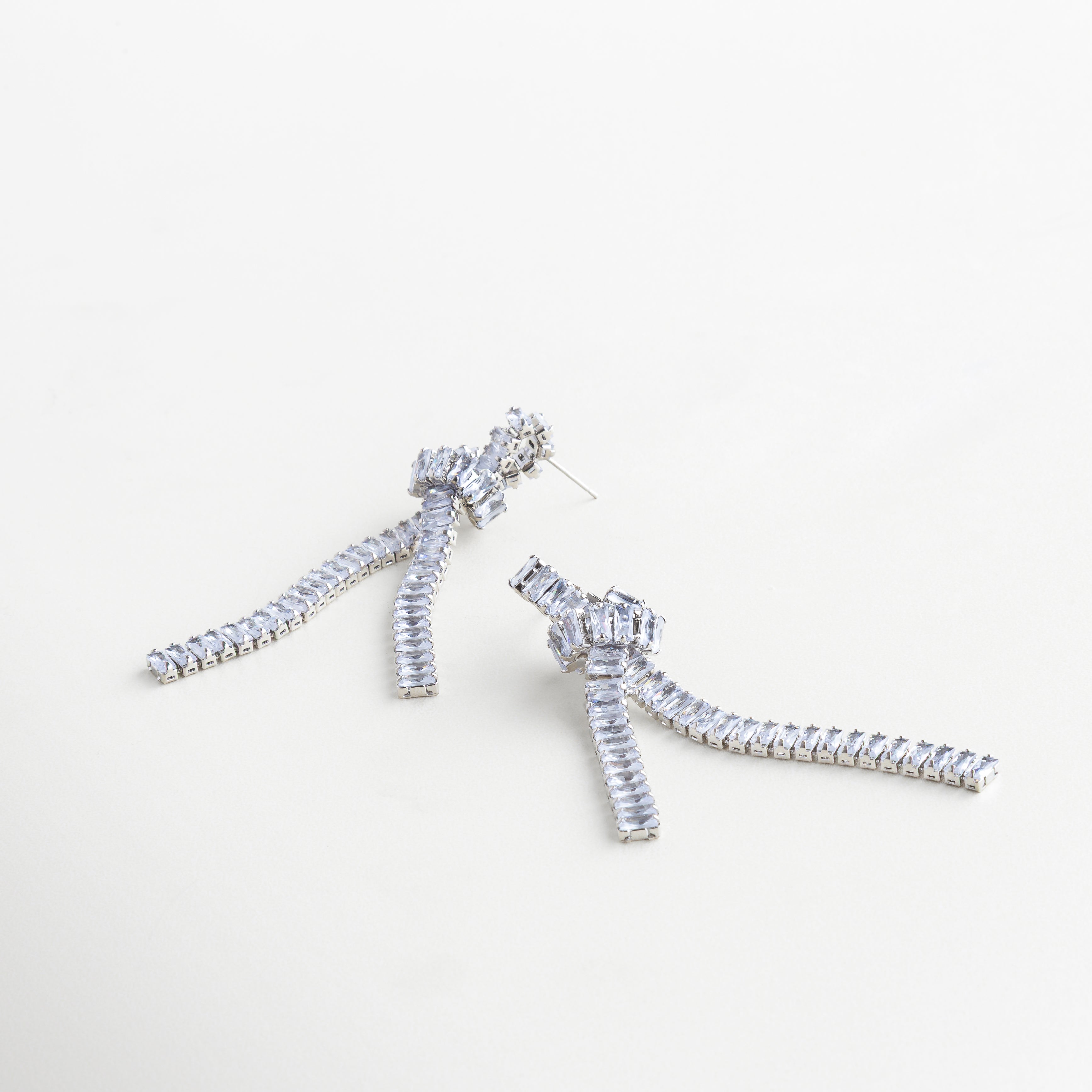 Aretes largos plateados usados, con caída de cadenas y zirconias, Aretes Noir Knot plateados con nudo metálico y toque sofisticado, Joyería plateada moderna con brillo sutil y diseño escultural, Aretes femeninos con caída de 8.7 cm y acabado brillante