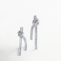 Aretes largos plateados con nudo y cadenas con zirconias, Aretes escultóricos plateados con nudo metálico y caída brillante, Aretes con diseño de nudo plateado y cadenas colgantes con gemas, Aretes Noir Knot plateados con zirconias y estructura elegante
