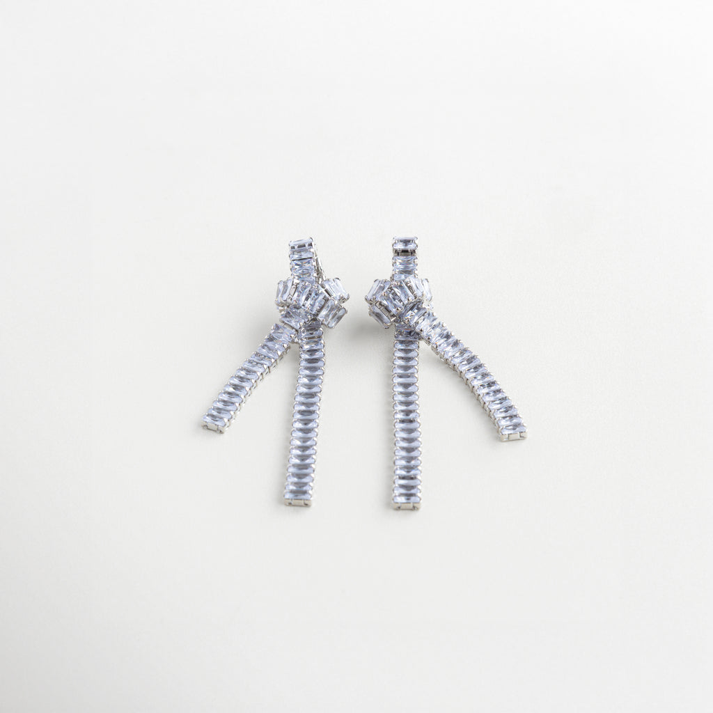 Aretes de 8.7 cm en tono plateado con diseño de cadena, Escala de aretes largos con nudo y gemas en plata, Aretes con caída brillante y estructura escultural plateada, Largo de aretes plateados con cadenas y zirconias
