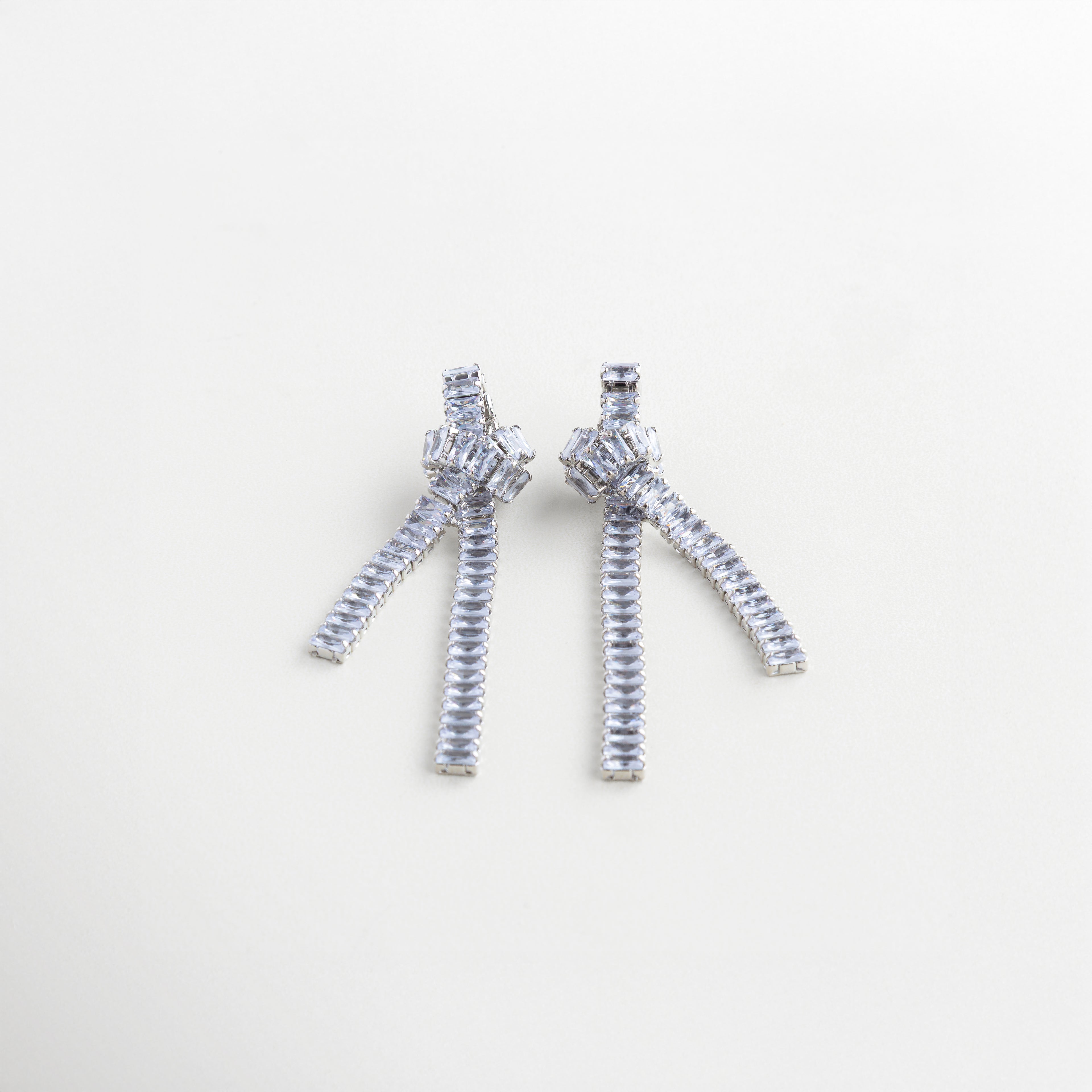Aretes de 8.7 cm en tono plateado con diseño de cadena, Escala de aretes largos con nudo y gemas en plata, Aretes con caída brillante y estructura escultural plateada, Largo de aretes plateados con cadenas y zirconias