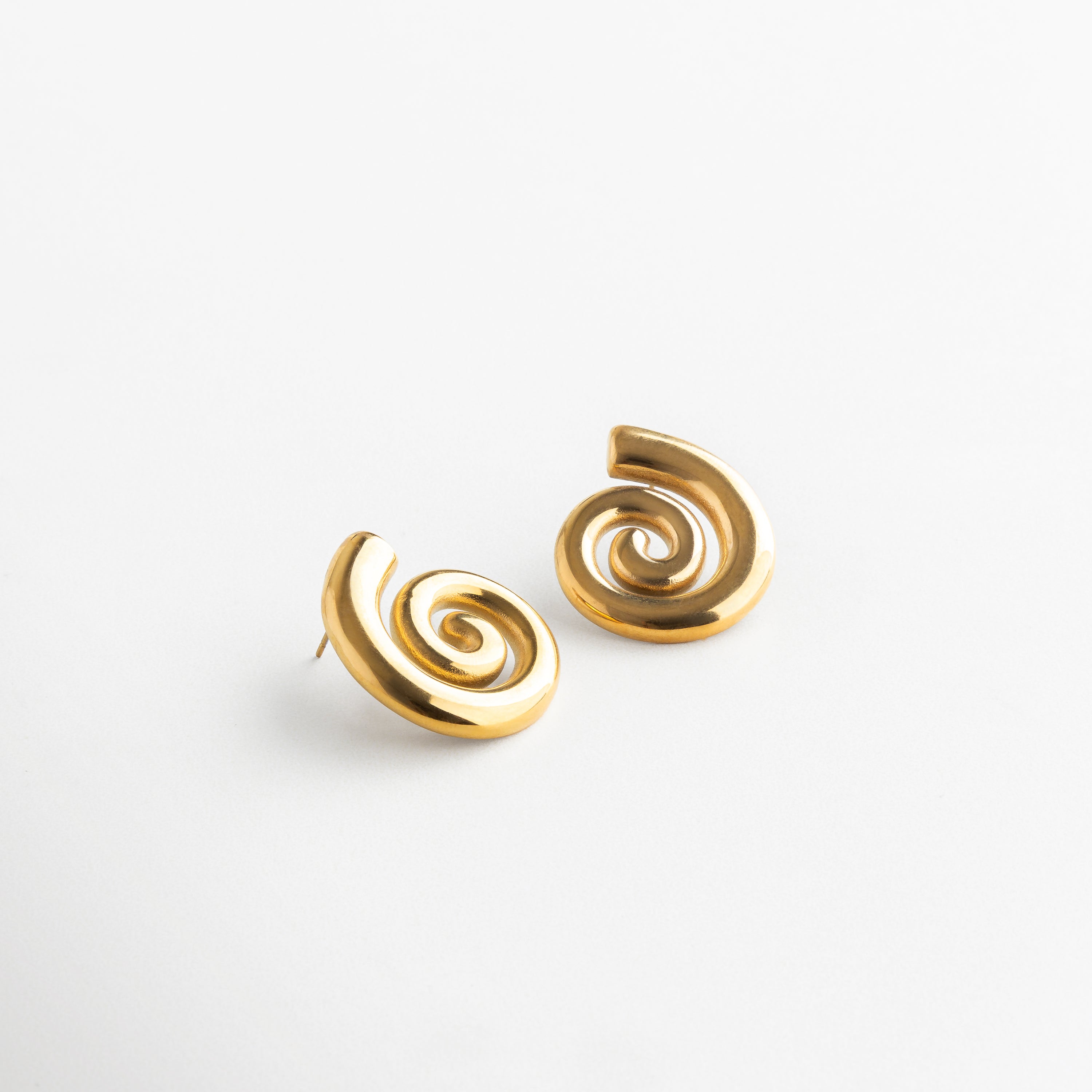 Detalle de la espiral dorada con acabado brillante, Close-up de diseño escultórico en espiral metálica dorada, Textura y forma fluida de arete en espiral con baño de oro, Silueta artística de arete dorado con movimiento visual