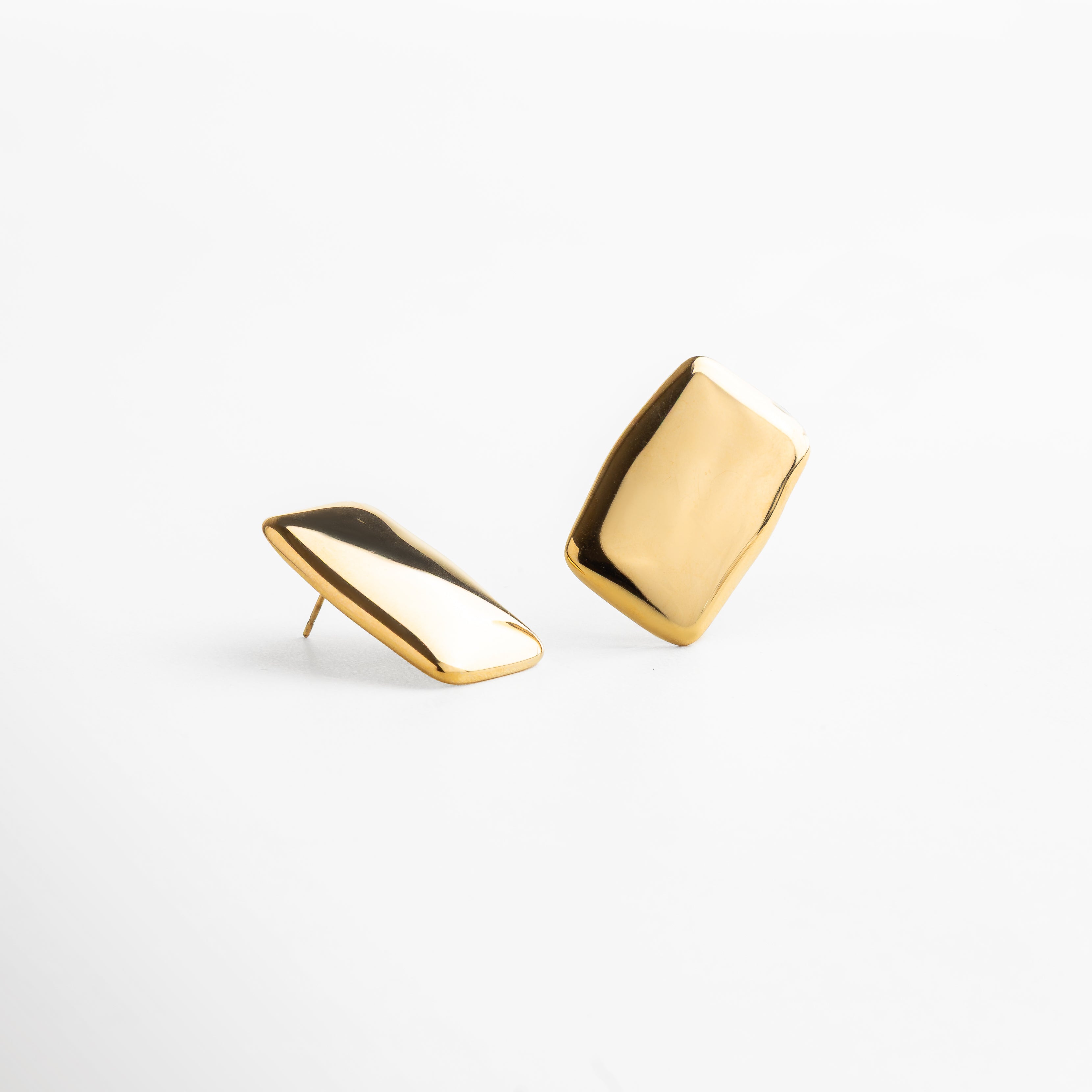 Detalle de aretes con acabado dorado brillante, silueta rectangular y líneas limpias, diseño que combina minimalismo y elegancia, accesorio perfecto para transformar cualquier outfit con sutileza