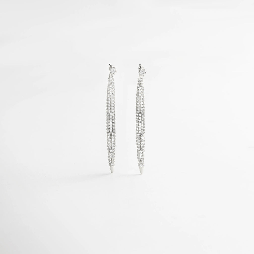 aretes largos vista frontal, joyería plateada minimal, aretes elegantes mujer, accesorios plateados sofisticados, aretes colgantes chic, joyería femenina luminosa, aretes finos plateados, aretes modernos