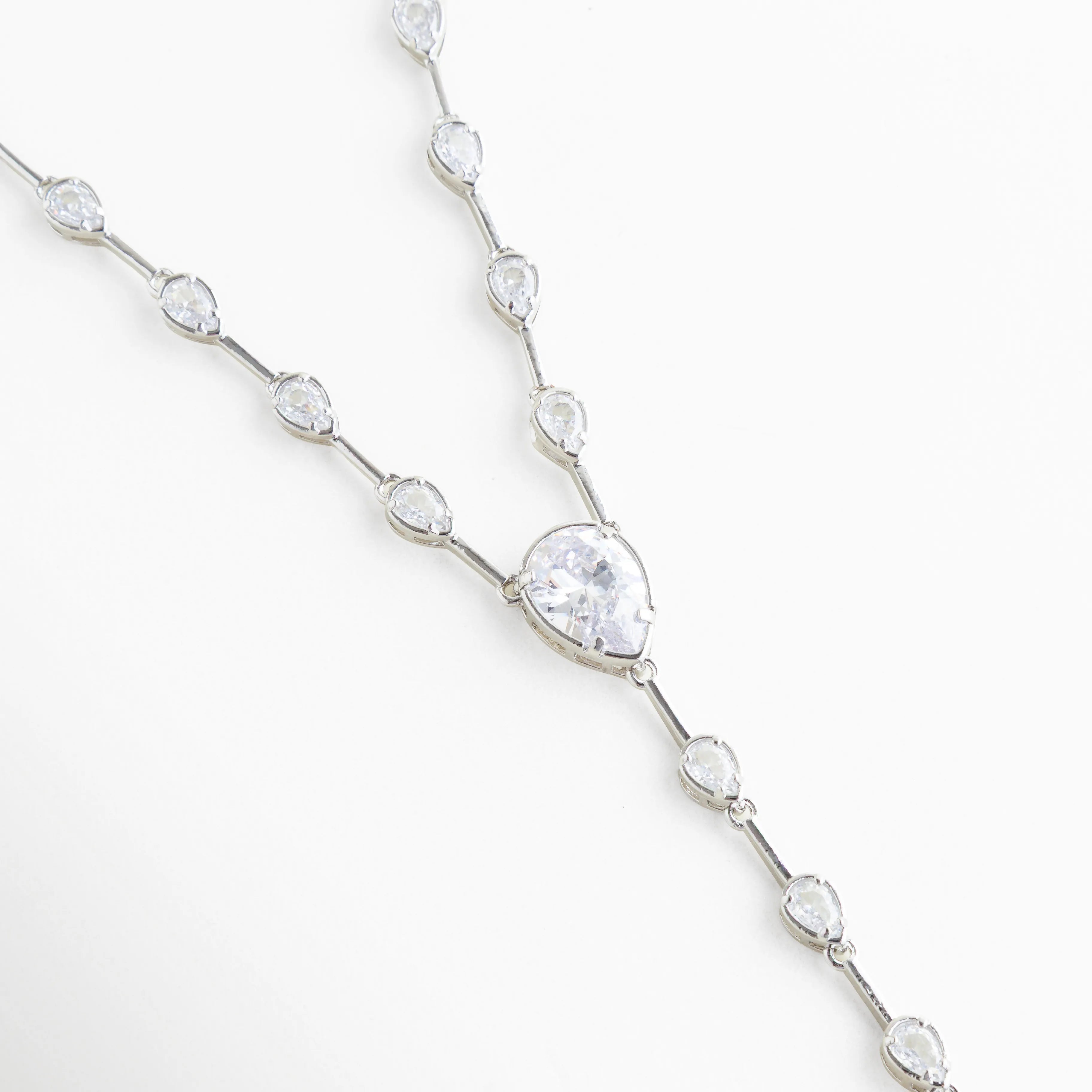 Detalle de cadena plateada con zirconias ovaladas incrustadas, Close up de collar con piedras brillantes tipo diamante, Cadena delicada con incrustaciones de zirconia y acabado en oro blanco, Detalle de eslabones con cristales brillantes en collar elegante, Vista cercana de zirconias en cadena fina plateada