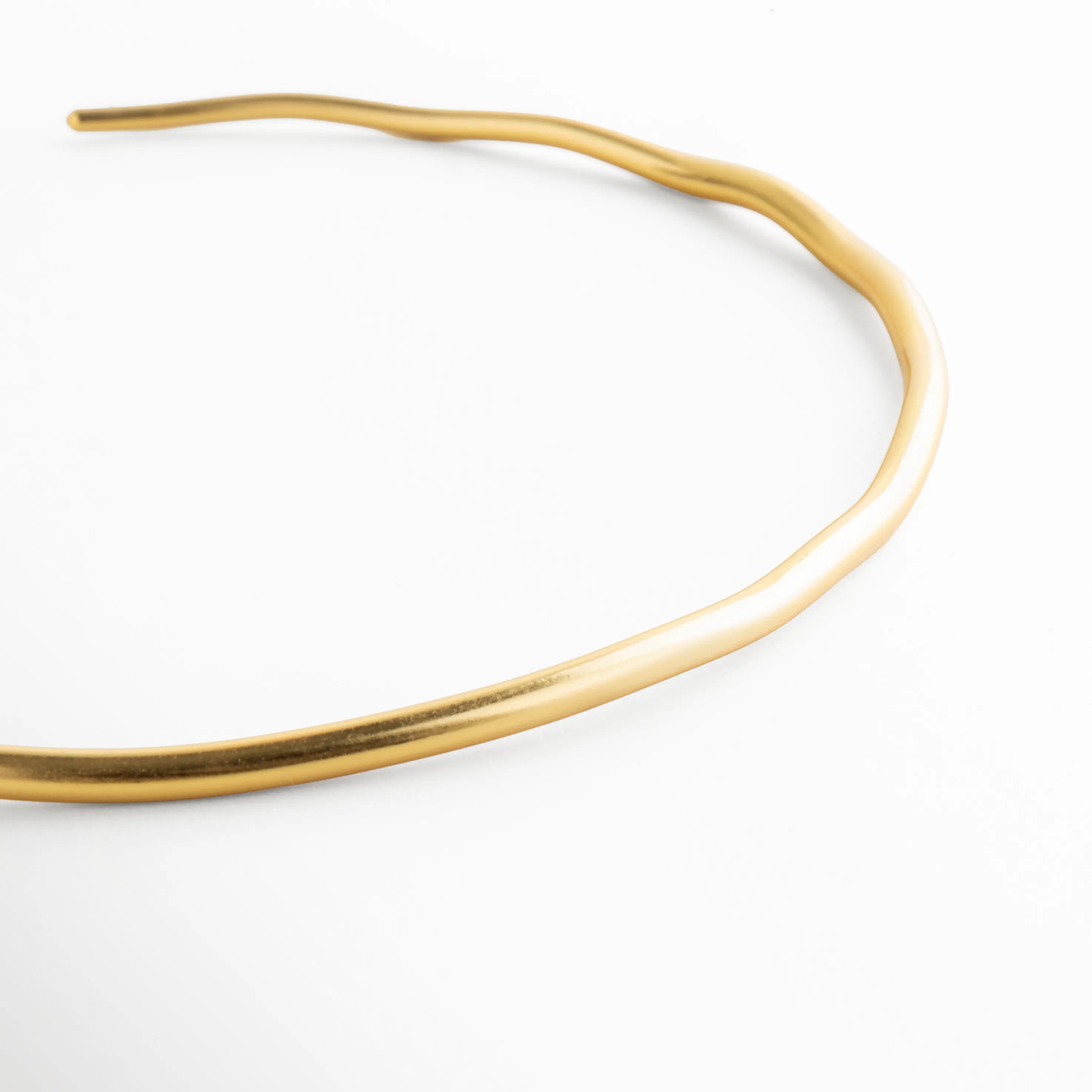Detalle collar dorado pulido con acabado brillante, Close up gargantilla dorada lisa diseño minimalista, Curvatura collar rígido dorado acabado espejo, Detalle superficie collar dorado elegante, Textura lisa collar choker dorado moderno