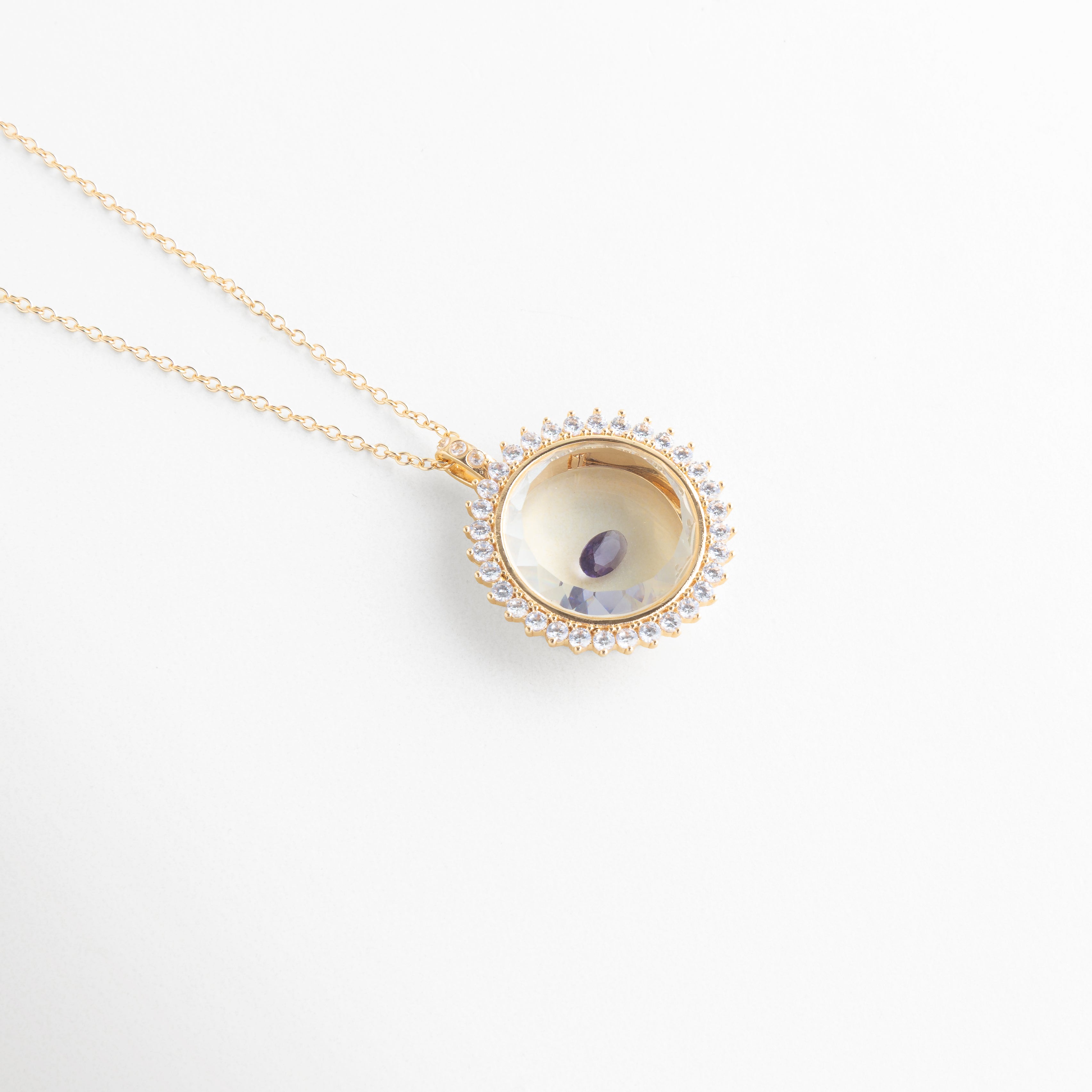 Collar dorado con dije circular y piedra de cristal morada central, Dije elegante con cristal púrpura brillante en diseño delicado, Joyería fina con piedra violeta en accesorio minimalista, Collar delicado con cristal morado pequeño y brillante, Accesorio de bisutería con gema morada en diseño moderno