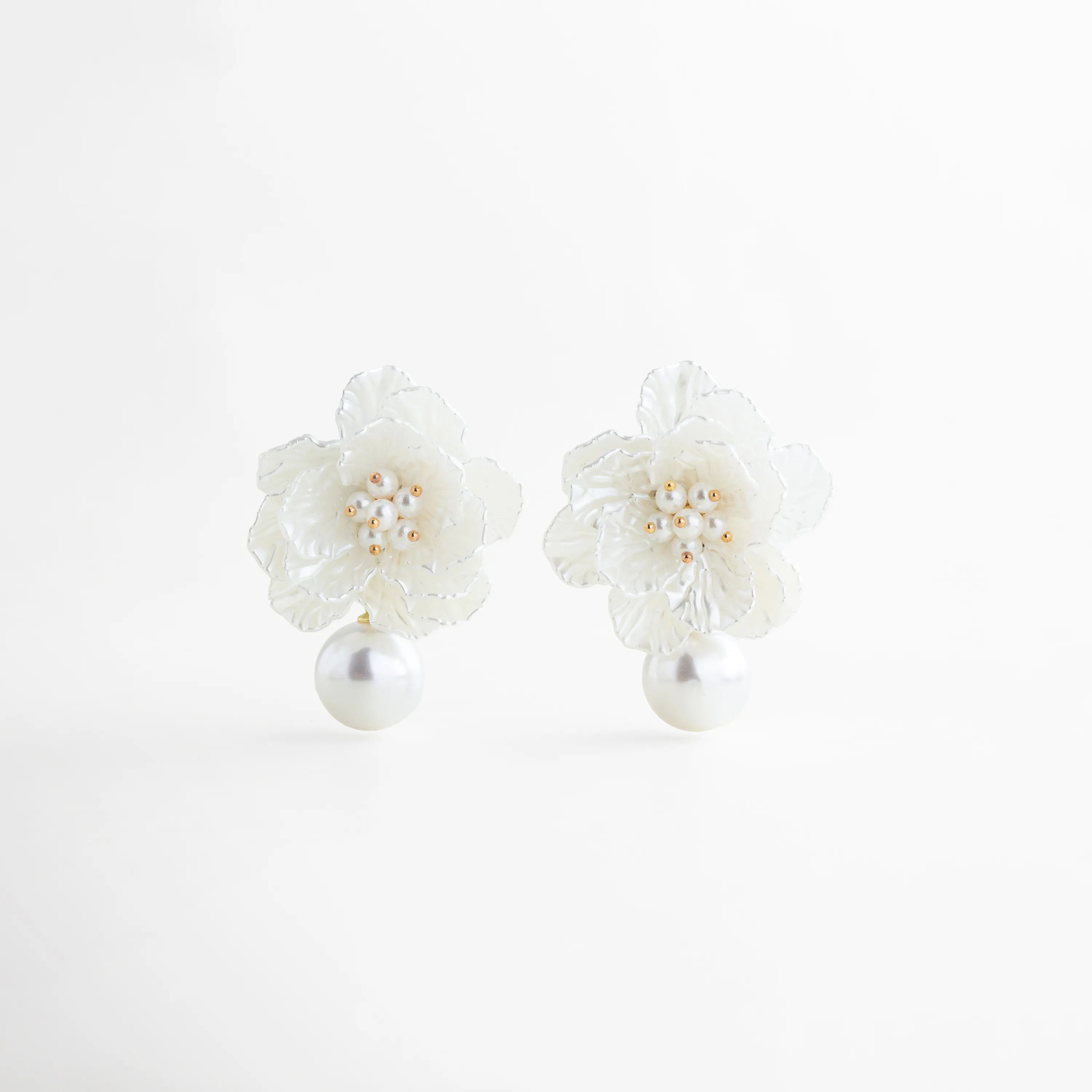 Aretes florales blancos con perla colgante y detalles dorados elegantes, Aretes Pearl Bloom con diseño de flor y perla grande estilo femenino, Aretes largos con flor blanca texturizada y perla colgante sofisticada, Aretes elegantes con forma de flor y perla brillante en tono blanco, Aretes statement florales con perla y acabado en oro blanco