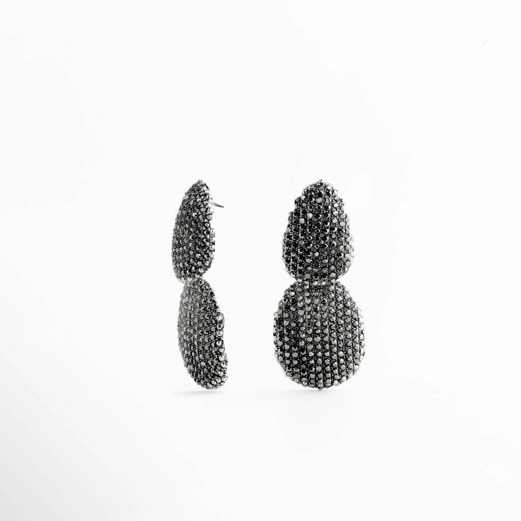 Aretes Silver Eira vista lateral con cristales pavé y acabado plateado brillante, Detalle de aretes plateados con incrustaciones pavé, diseño glam elegante, Aretes largos plateados con textura de cristales pavé en vista cercana, Aretes sofisticados en tono plata con doble volumen y acabado brillante pavé, Vista lateral de aretes glam con cristales pavé y diseño elegante en bisutería