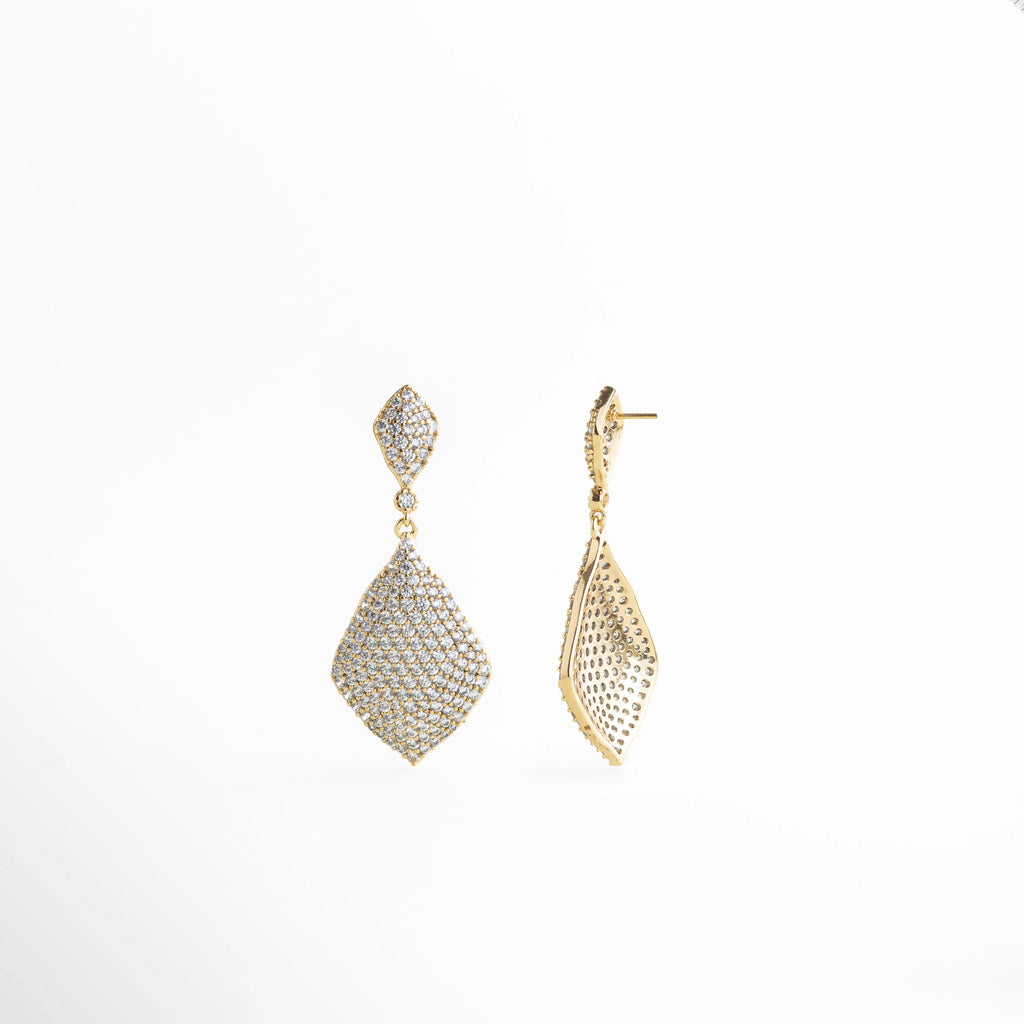 Aretes Aurielle dorados con zirconia en detalle, acabado brillante y glam, Detalle de Aretes Aurielle con zirconia y textura luminosa en oro 18K, Aretes Aurielle con diseño colgante y zirconia brillante en vista cercana, Aretes Aurielle elegantes con acabado dorado y zirconia de alto brillo, Primer plano de Aretes Aurielle con incrustaciones de zirconia y estilo lujo