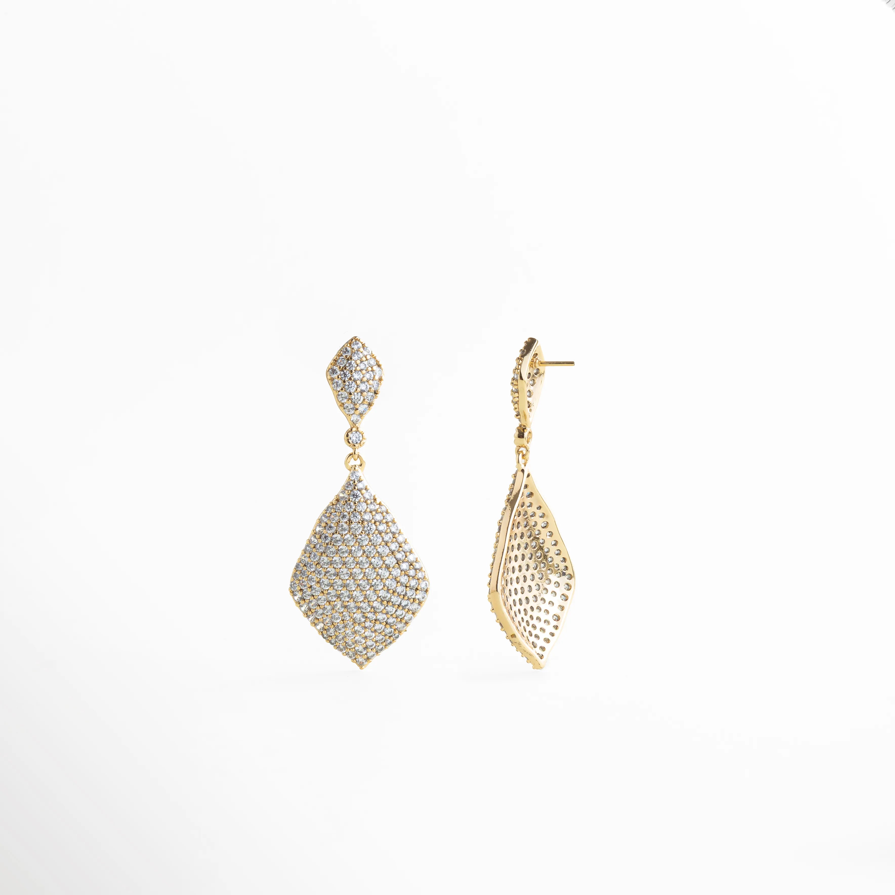 Aretes Aurielle dorados con zirconia en detalle, acabado brillante y glam, Detalle de Aretes Aurielle con zirconia y textura luminosa en oro 18K, Aretes Aurielle con diseño colgante y zirconia brillante en vista cercana, Aretes Aurielle elegantes con acabado dorado y zirconia de alto brillo, Primer plano de Aretes Aurielle con incrustaciones de zirconia y estilo lujo