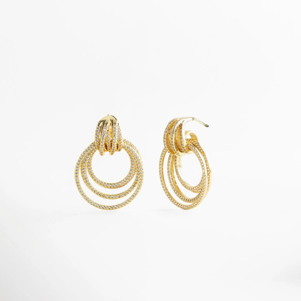 Aretes Elarisse dorados vista lateral con zirconias y aros múltiples, Detalle lateral de Aretes Elarisse con diseño de aros y brillo en zirconias, Aretes Elarisse colgantes dorados con estructura circular en perfil, Aretes Elarisse elegantes con capas de aros y acabado en oro 18K, Vista lateral de Aretes Elarisse glam con zirconias y diseño sofisticado