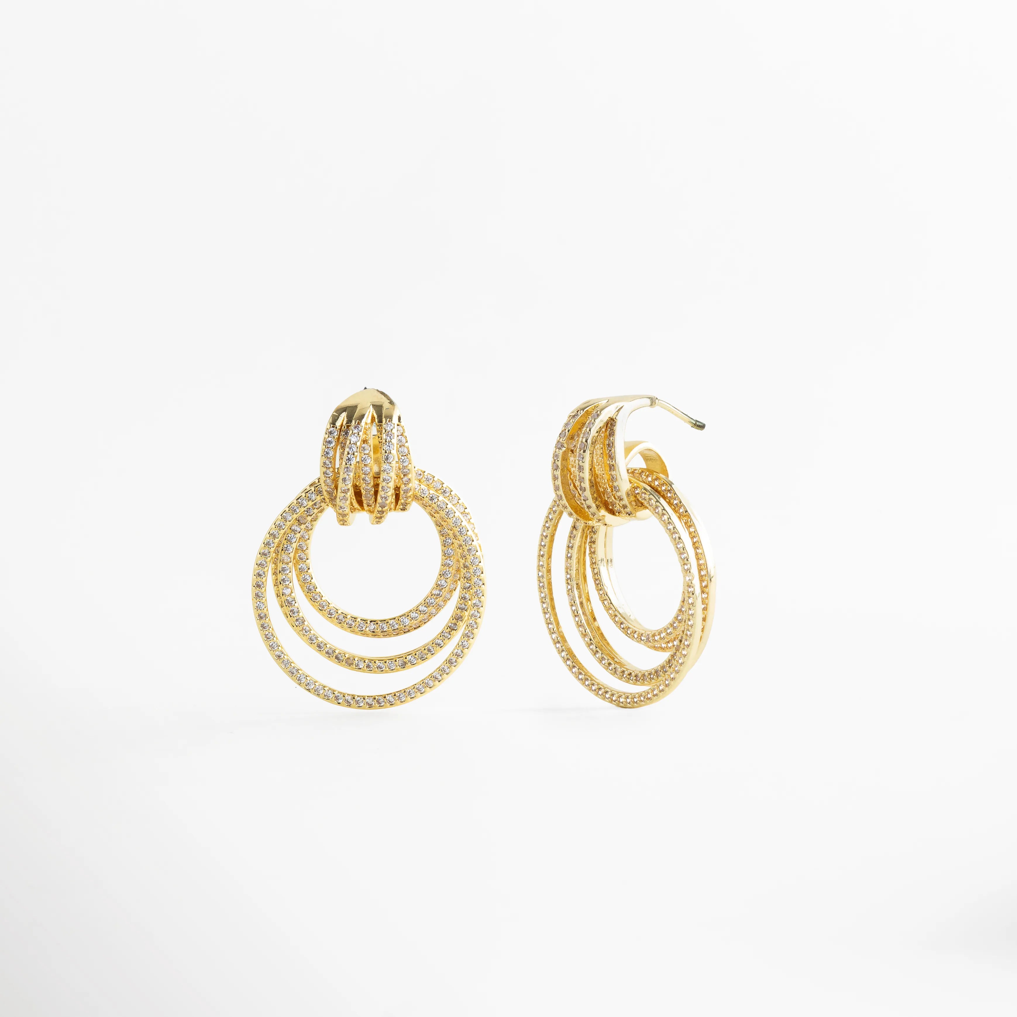 Aretes Elarisse dorados vista lateral con zirconias y aros múltiples, Detalle lateral de Aretes Elarisse con diseño de aros y brillo en zirconias, Aretes Elarisse colgantes dorados con estructura circular en perfil, Aretes Elarisse elegantes con capas de aros y acabado en oro 18K, Vista lateral de Aretes Elarisse glam con zirconias y diseño sofisticado