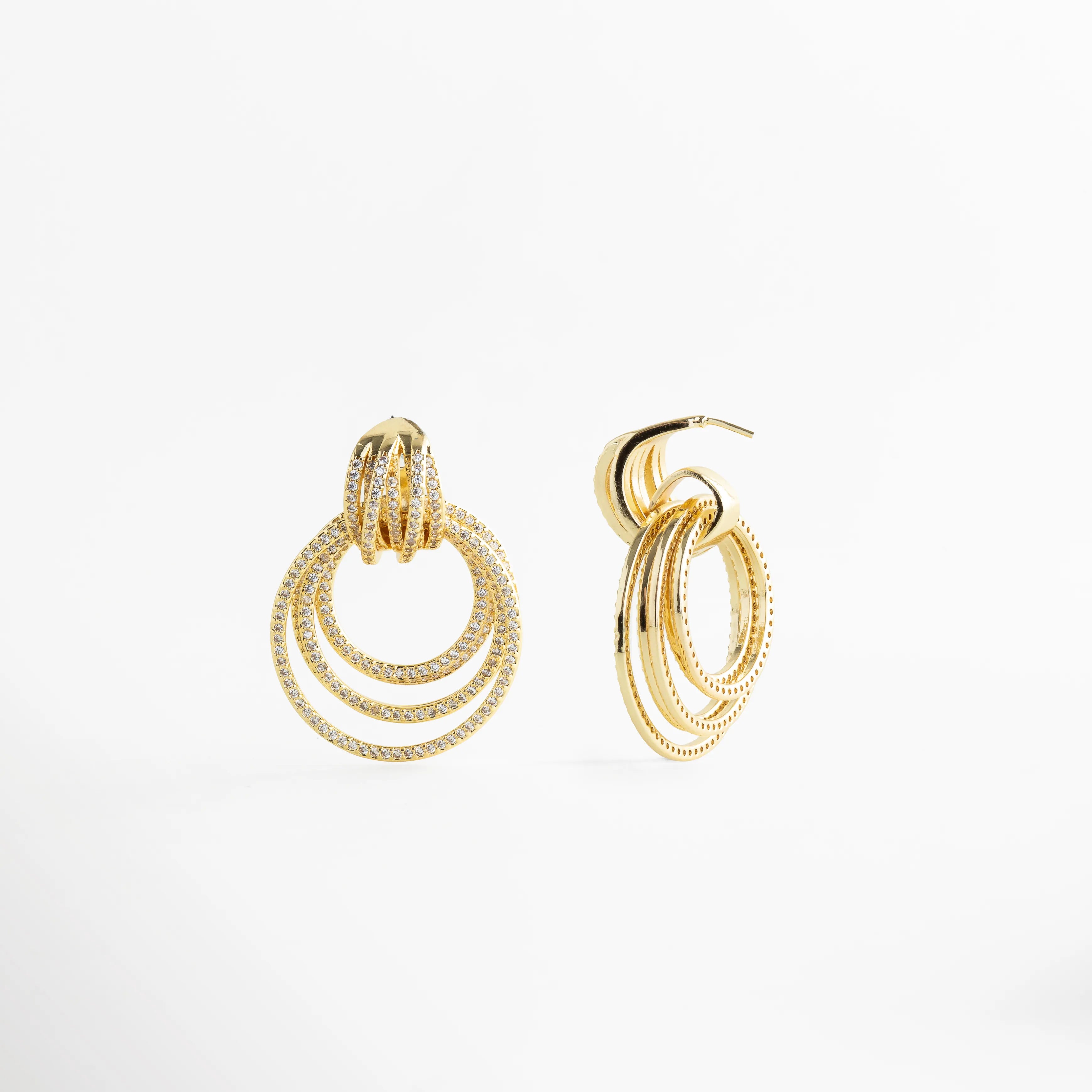 Aretes Elarisse dorados con zirconias en detalle, diseño de aros brillantes, Detalle de Aretes Elarisse con zirconias y acabado en oro 18K luminoso, Aretes Elarisse con diseño circular en capas y zirconias en vista cercana, Aretes Elarisse elegantes con brillo intenso y textura en zirconias, Primer plano de Aretes Elarisse dorados con diseño glam y zirconias