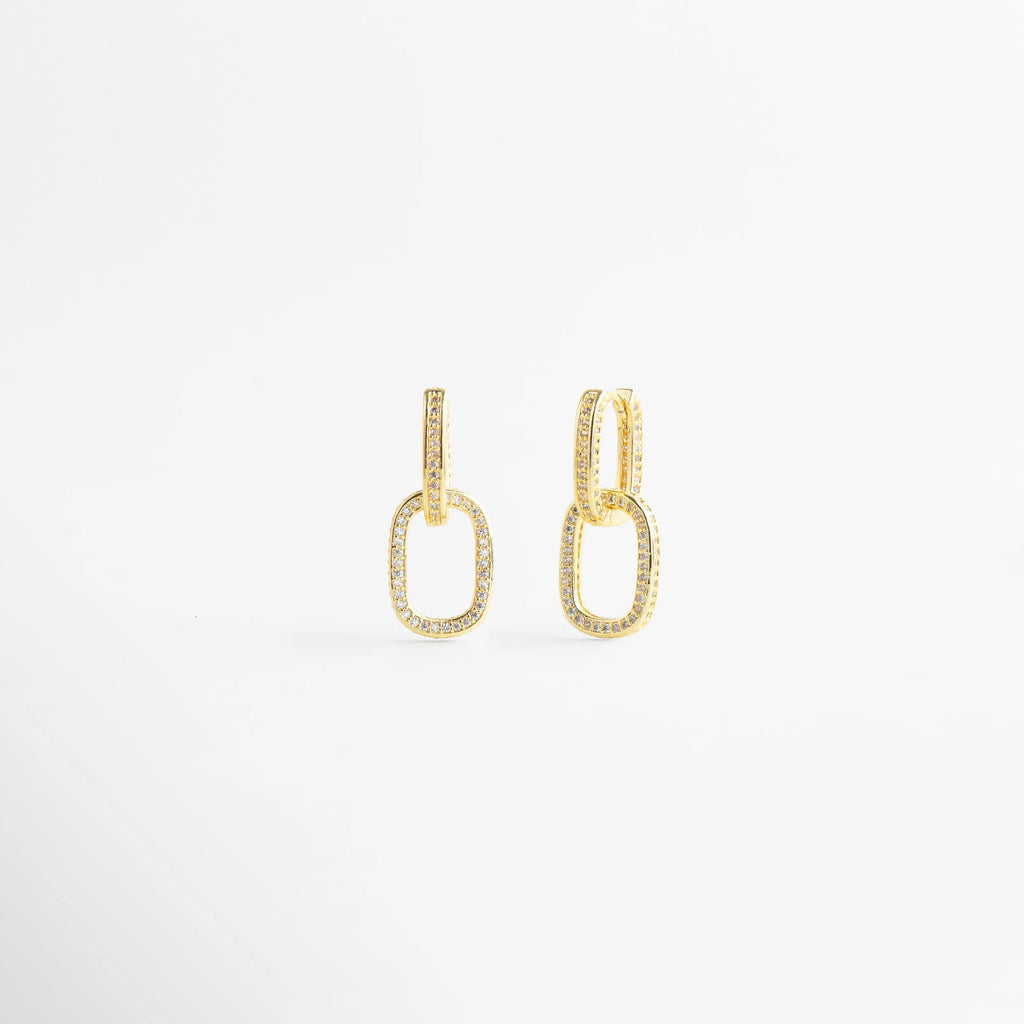 Par de aretes de eslabones dorados con cristales vistos desde un ángulo lateral, Pendientes de aro con diseño de cadena y piedras brillantes en perspectiva, Detalle lateral de arracadas ovaladas de oro con incrustaciones de circonitas, Joyería de moda: pendientes de eslabón brillante con acabado en oro pulido, Accesorios para mujer: aretes de eslabón doble con cristales en vista diagonal.