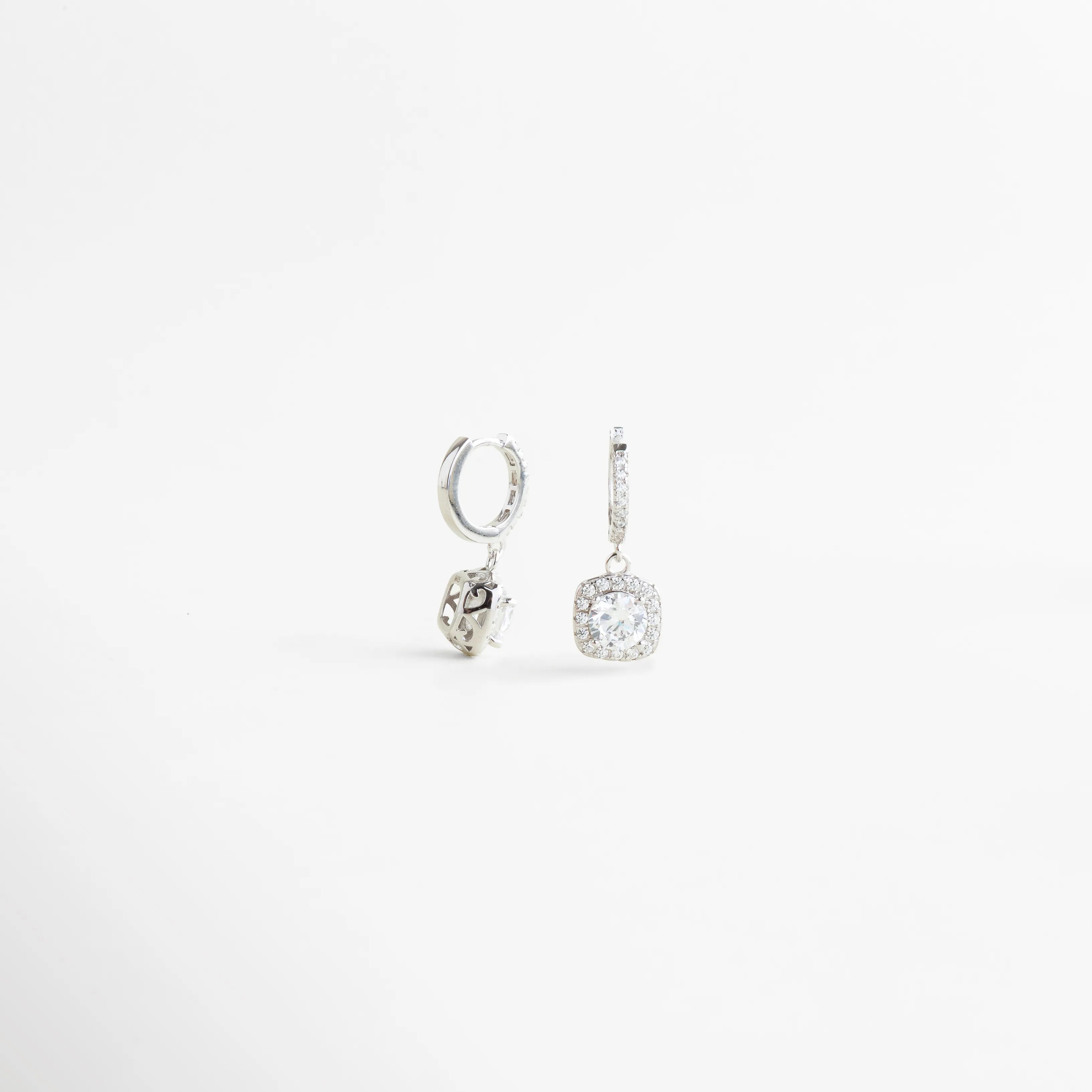 Detalle del aro de aretes en Plata Ley 925 con colgante de zirconia brillante, Vista cercana de aretes delicados con estructura fina y zirconia luminosa, Detalle de aretes tipo hoop pequeños con piedra colgante y acabado sofisticado, Aretes de plata con diseño refinado y zirconia brillante en detalle lateral, Estructura elegante de aretes colgantes con acabado pulido y estilo femenino.