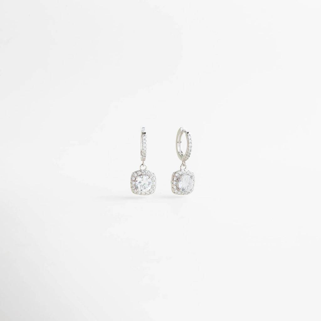 Aretes de zirconia en vista diagonal con diseño colgante y acabado elegante en plata, Vista lateral de aretes femeninos con aro pequeño y zirconia brillante colgante, Aretes delicados de Plata Ley 925 mostrados en ángulo para destacar su brillo y forma, Diseño sofisticado de aretes colgantes con zirconia redonda y acabado refinado, Aretes elegantes para mujer con caída sutil y piedra brillante en vista diagonal.