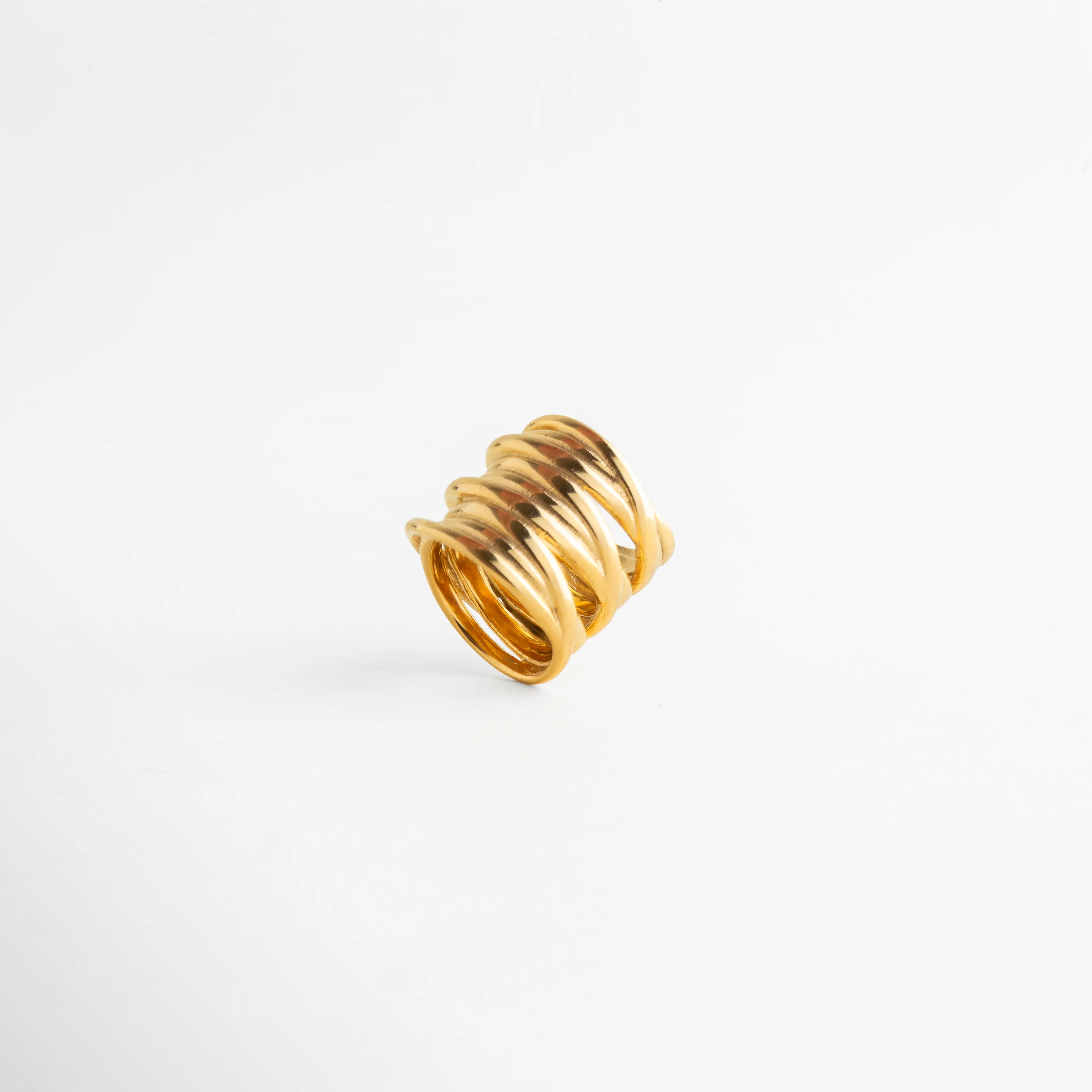 Vista inclinada del Anillo Halo con diseño envolvente y acabado dorado brillante, Anillo moderno en tono oro visto en ángulo con líneas orgánicas entrelazadas, Vista diagonal de anillo elegante con estilo creativo y sofisticado, Anillo femenino dorado con estructura ancha y diseño contemporáneo, Detalle angular del Anillo Halo con silueta moderna y acabado pulido.