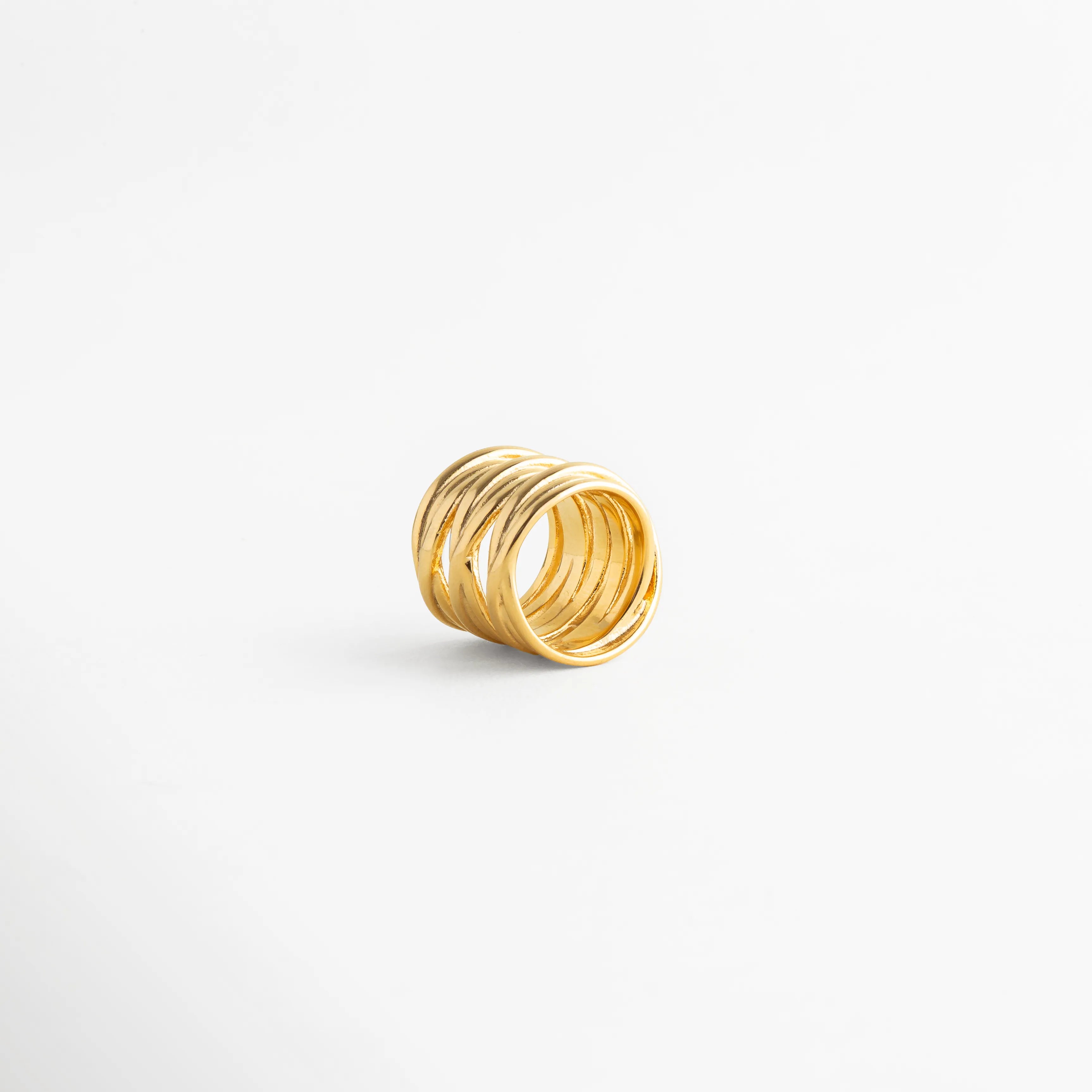 Vista lateral del Anillo Halo con diseño ancho y acabado en Oro 18K, Perfil de anillo dorado con líneas cruzadas y estilo refinado, Anillo ancho de acero inoxidable visto de lado con diseño minimalista, Vista de perfil de anillo statement con estética moderna y elegante, Detalle lateral del Anillo Halo con acabado pulido y silueta estructurada.