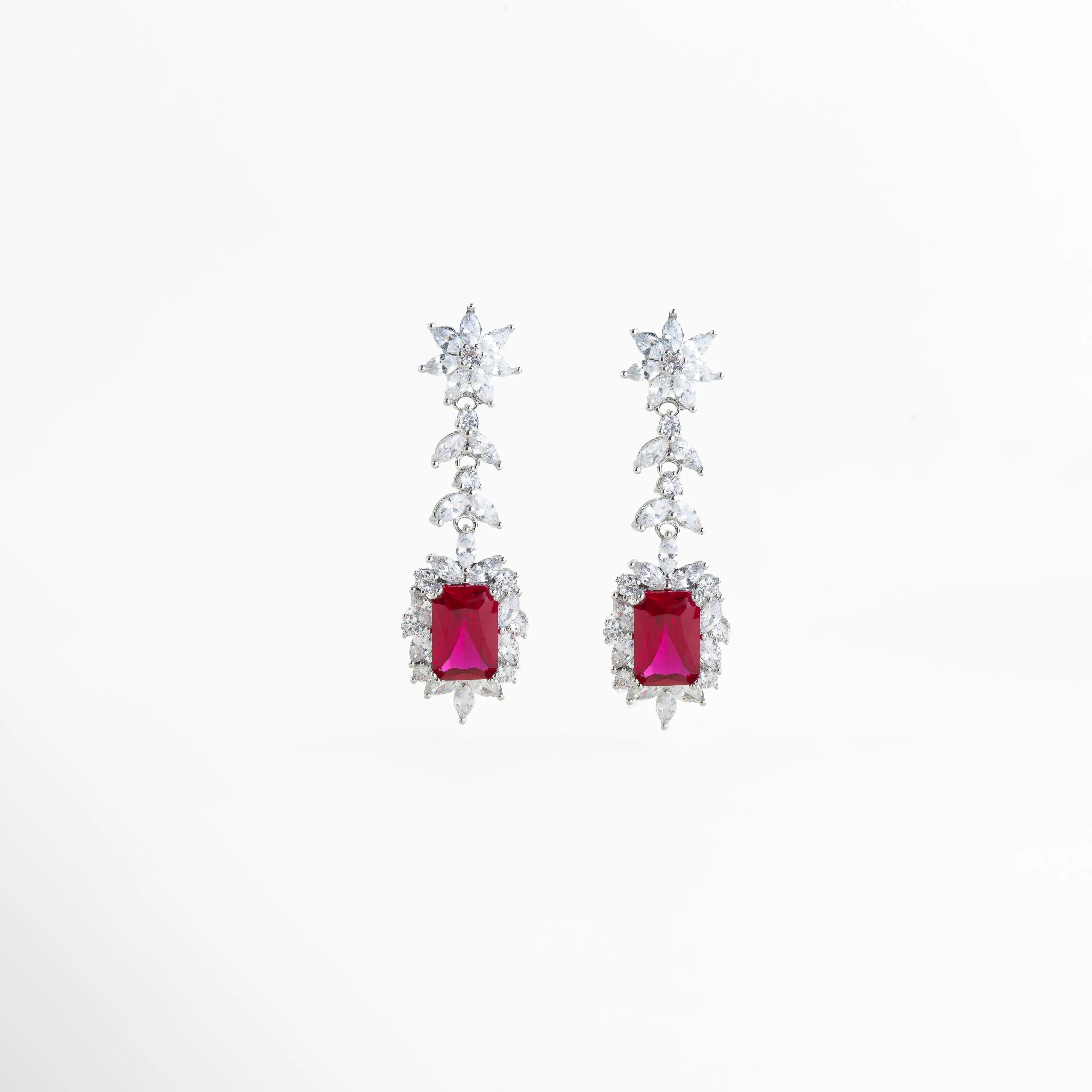 Aretes largos en acabado de plata de rodio con gema central roja y halo de circonias brillantes, Pendientes de gala con piedra roja rectangular y diseño de hojas de cristal en cascada, Vista frontal de aretes elegantes de 5 cm de largo con circonias blancas y centro color rubí, Joyería de lujo: aretes con recubrimiento de rodio y piedras preciosas de imitación en color rojo, Par de aretes Rojos resaltando el corte esmeralda de la gema central y el brillo del pavé.