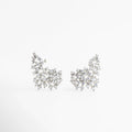 Aretes Nevada de cobre con acabado en rodio y diseño de ala de ángel con circonias, Par de aretes asimétricos con incrustaciones de zirconia blanca sobre fondo neutro, Vista frontal de aretes elegantes con estructura orgánica y brillo intenso de cristales, Joyería de rodio: aretes de 2.6 cm de largo con diseño femenino y sofisticado, Detalle de aretes "Nevada" resaltando el patrón de piedras entrelazadas en forma de ala.