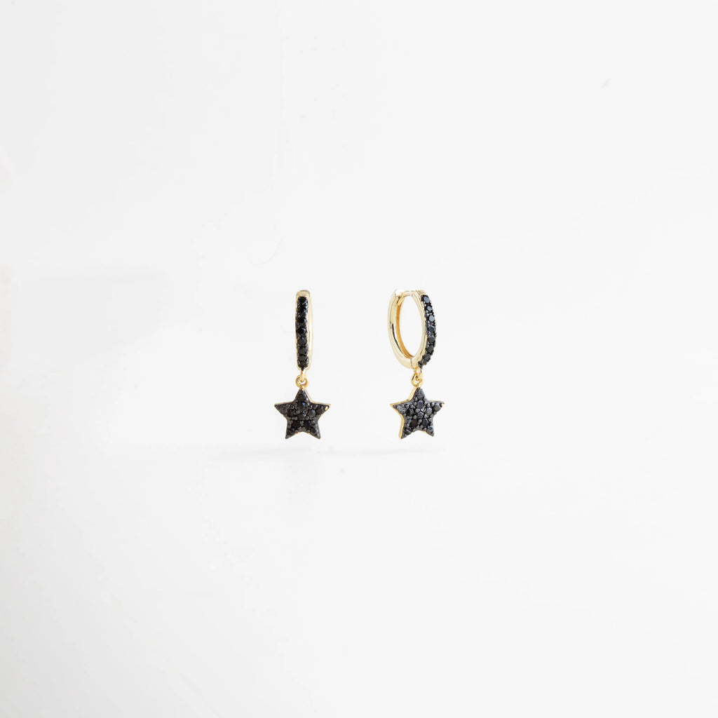 Detalle en ángulo de la estrella con zirconias negras resaltando el contraste con el oro, Vista de tres cuartos de las arracadas doradas con dije de estrella brillante y oscura, Perspectiva de aretes de 2.5 cm de largo con diseño de astro y cristales negros, Enfoque en el brillo de las micro-zirconias negras en la estructura dorada de la estrella, Relieve del dije de estrella en aretes de chapa de oro con diseño de vanguardia.