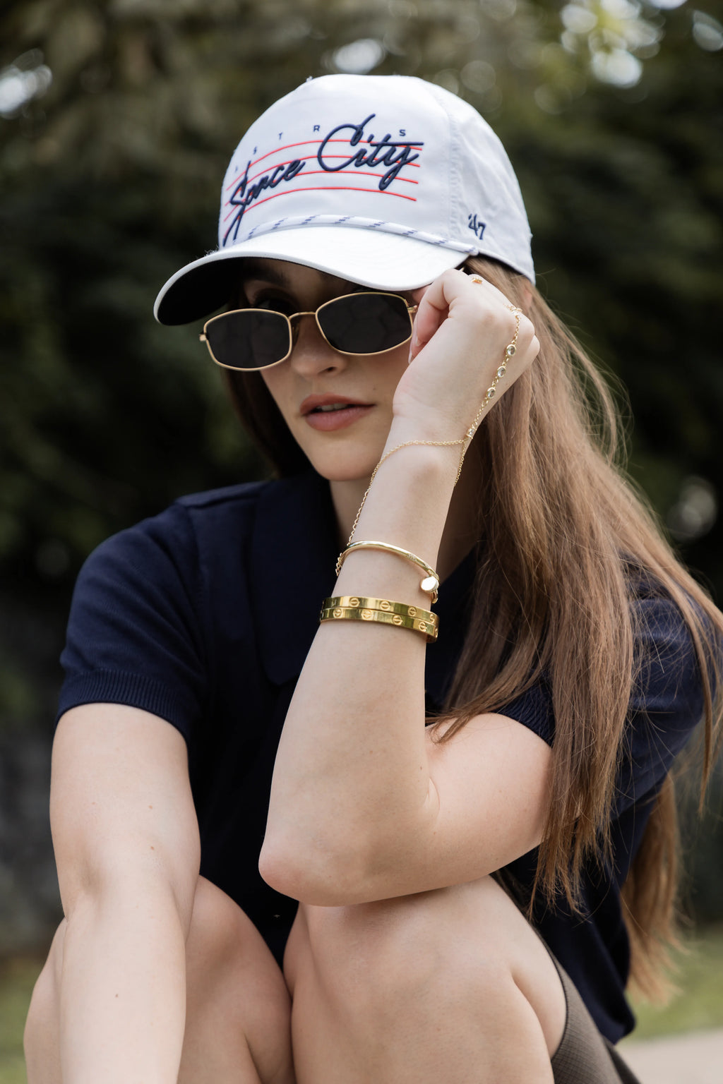 brazaletes dorados con silueta bold que equilibran el look con un toque sofisticado. La mezcla con la gorra y las gafas crea una estética moderna, fresca y segura de sí misma. Ideal para quienes buscan elevar lo casual sin perder naturalidad.