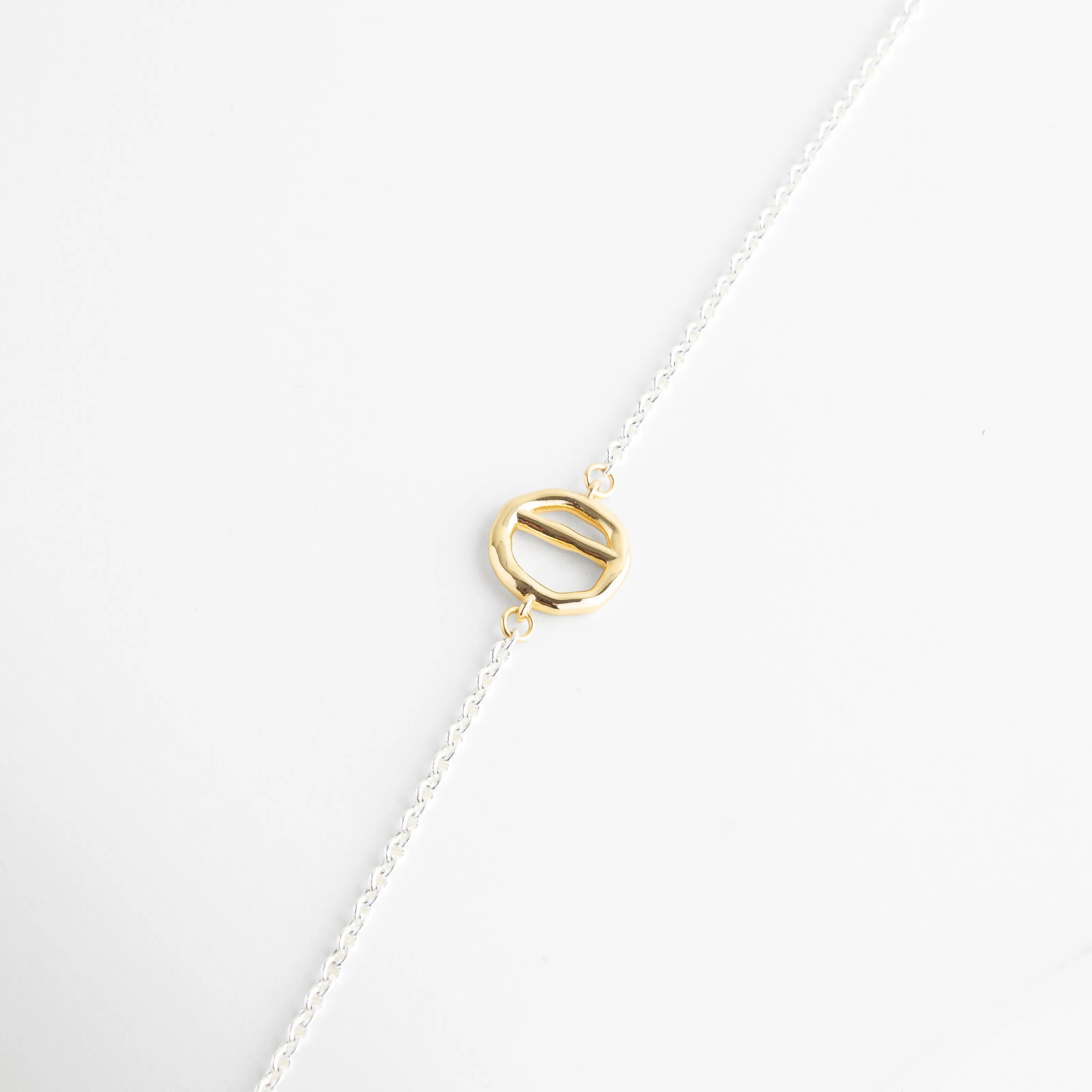Composición de las piezas del collar: cierre T-Bar, placa circular y cadena platinada, Muestra de los elementos dorados de 18K que componen el collar bi-color de 37 cm, Vista detallada de los herrajes dorados sobre el fondo blanco de joyería fina, Separación visual de los dijes geométricos y la cadena de oro blanco 18K, Detalle de los acabados mixtos en collar de cobre con recubrimiento de lujo.