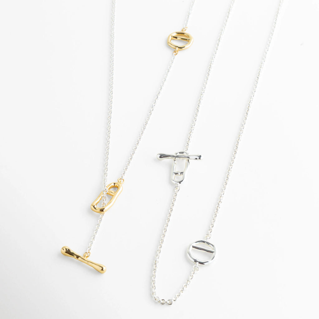Comparación de collar geométrico en oro amarillo 18K y oro blanco platinado, Variantes de color para collar lariat: opciones en dorado y plata brillante, Exhibición de acabados metálicos mixtos para colección de joyería minimalista, Dos estilos de collar T-bar: enchapado en oro vs. recubrimiento de oro blanco, Muestra de opciones de materiales para collar asimétrico de 37 cm de largo