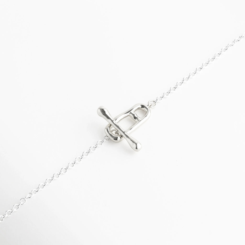 Cierre frontal tipo marinero (T-bar) enchapado en oro blanco de 18K, Broche de barra minimalista integrado al diseño de collar de plata fina, Detalle de funcionalidad y estética en collar con cierre de barra y aro, Sistema de cierre frontal decorativo en collar de cobre platinado de alta calidad, Foco en el pasador plateado de diseño orgánico para collar minimalista.