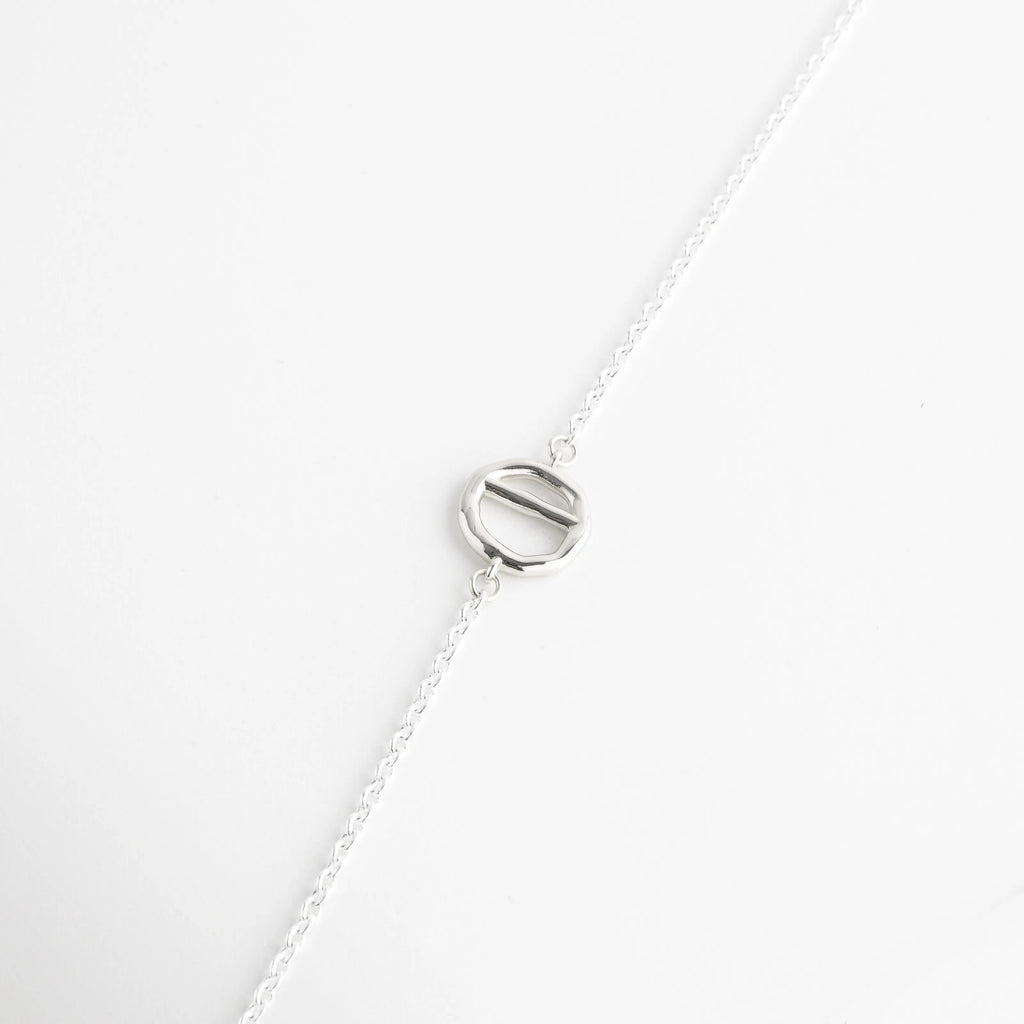 Dije circular minimalista de oro blanco insertado en cadena de eslabones delgados, Detalle de pieza redonda con barra central en collar de acabado platinado premium, Acento geométrico de 18K oro blanco sobre fondo blanco para joyería fina, Primer plano de elemento decorativo circular en collar moderno de 37 cm, Componente de diseño industrial elegante en collar de cobre con baño de oro blanco.