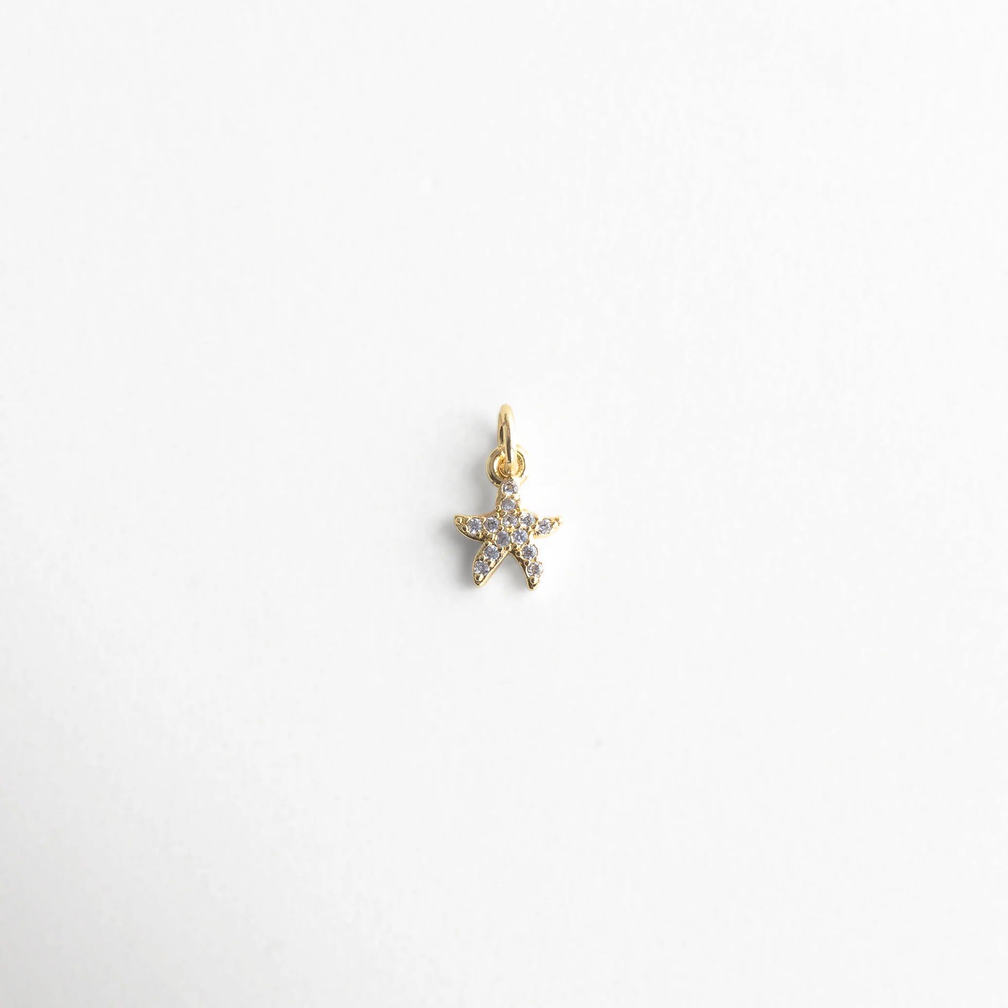 Dije dorado en forma de estrella de mar con incrustaciones brillantes, Charm de estrella de mar con zirconias, diseño elegante y delicado, Colgante dorado con cristales en forma de estrella marina, ideal para looks veraniegos.