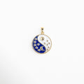 Charm dorado con diseño yin yang en tonos azul y blanco, decorado con sol, luna y estrellas esmaltadas, colgante con zirconias brillantes que representan el equilibrio entre la luz y la oscuridad, ideal para atraer armonía y energía positiva