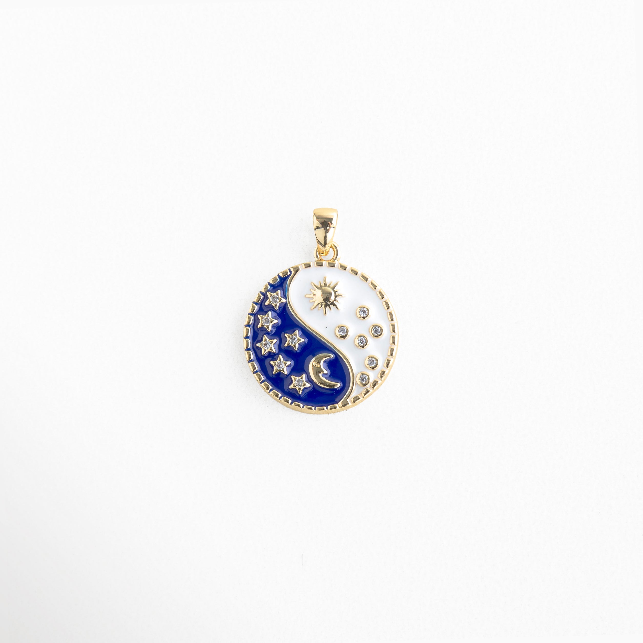 Charm dorado con diseño yin yang en tonos azul y blanco, decorado con sol, luna y estrellas esmaltadas, colgante con zirconias brillantes que representan el equilibrio entre la luz y la oscuridad, ideal para atraer armonía y energía positiva