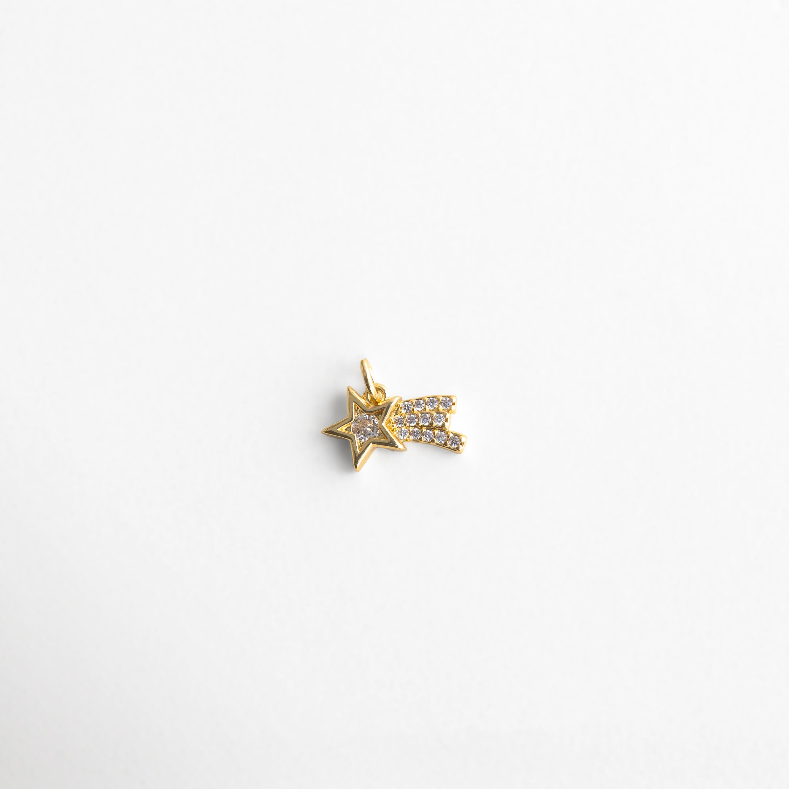 Charm dorado en forma de estrella fugaz con incrustaciones de zirconias, diseño brillante y elegante que simboliza deseos y nuevos comienzos, ideal para quienes buscan un toque celestial y lleno de luz en su estilo