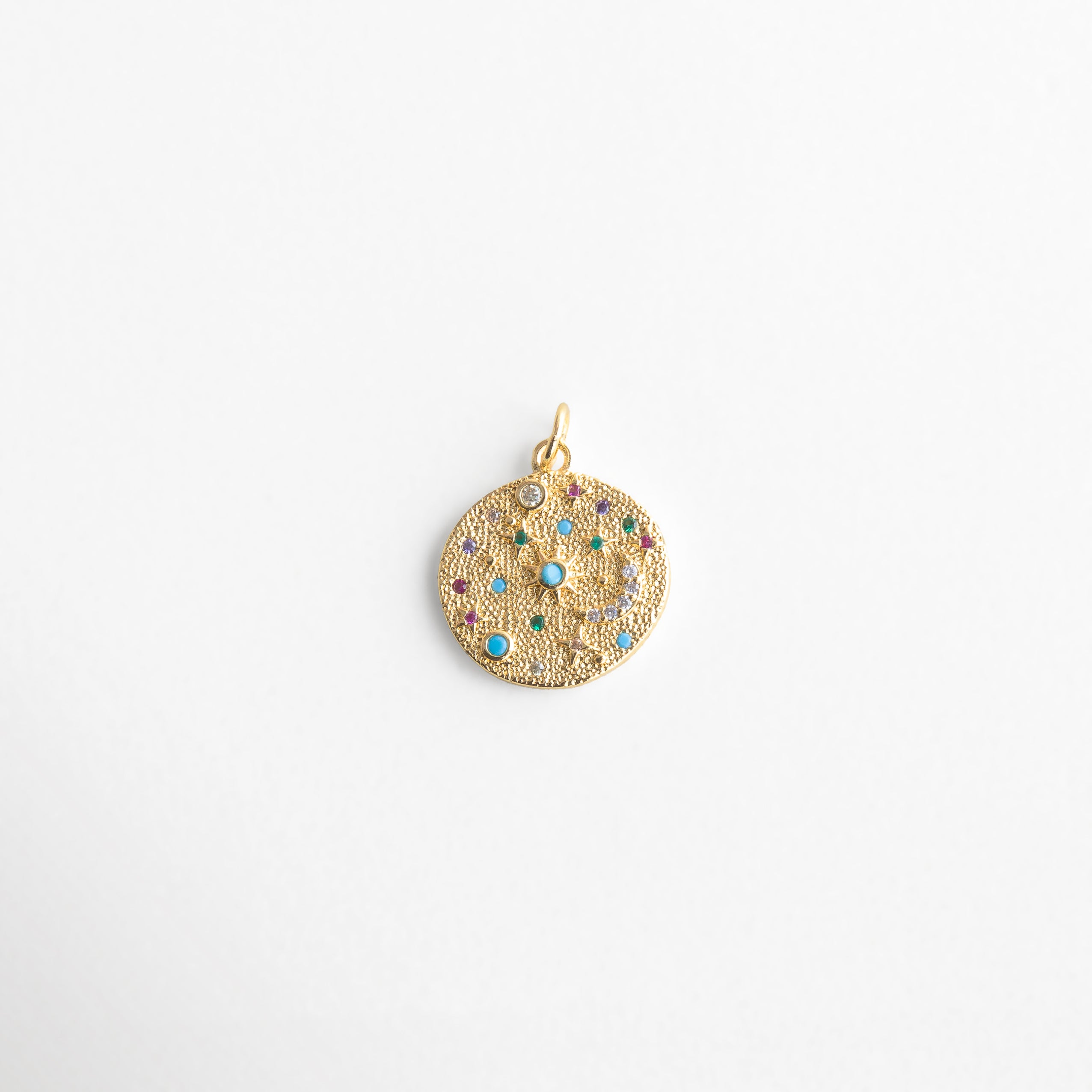 Charm dorado con diseño celestial y piedras multicolor, colgante redondo con textura brillante y detalles de zirconias en tonos turquesa, morado y verde, ideal para atraer energía positiva y darle un toque místico al estilo diario