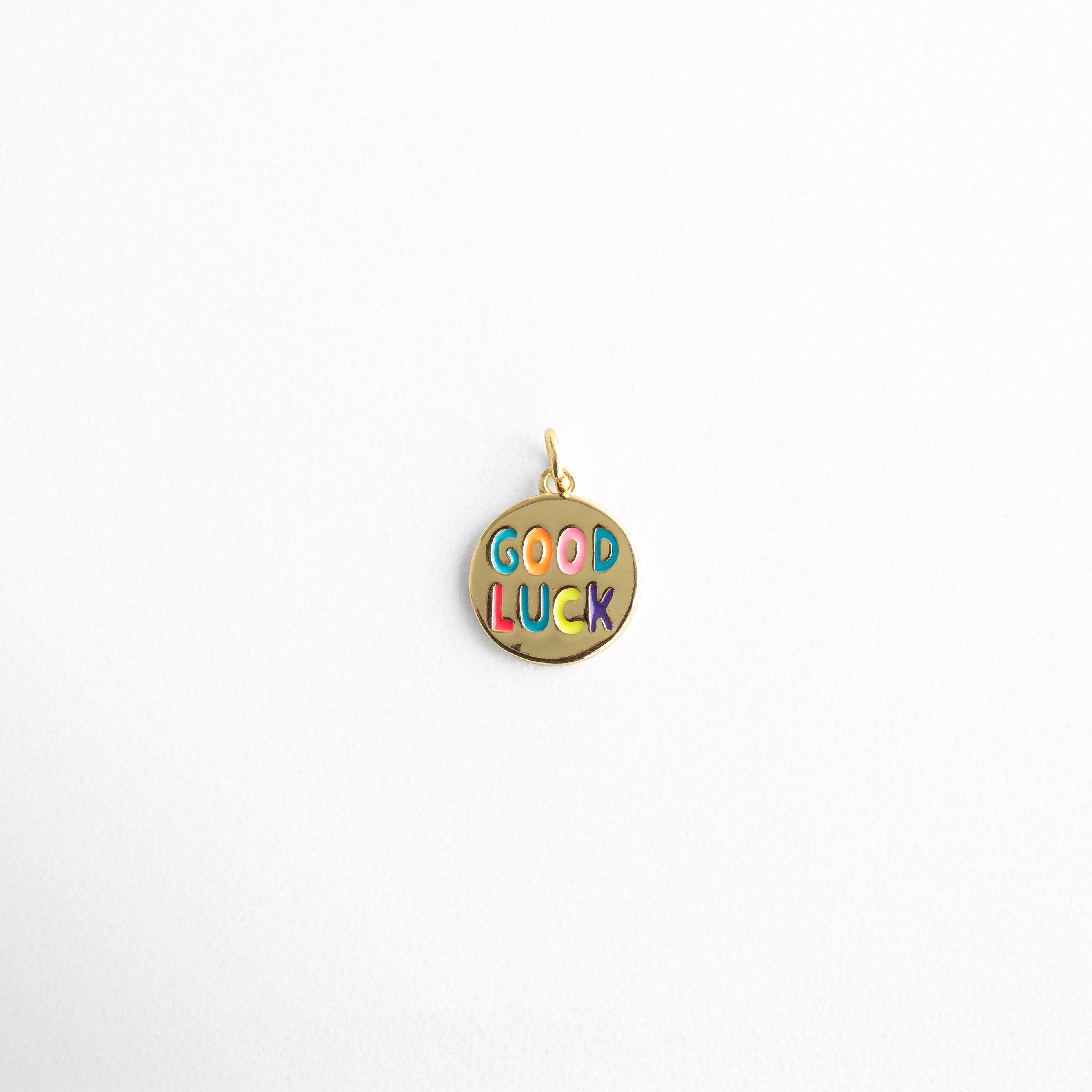 Charm dorado circular con la frase “GOOD LUCK” en colores esmaltados, diseño divertido y lleno de energía positiva, ideal para atraer buena suerte y añadir un toque colorido y alegre a cualquier look