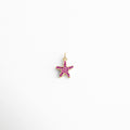 Charm dorado en forma de estrella de mar con incrustaciones de zirconias rosas, diseño delicado y veraniego, ideal para quienes aman el mar y buscan un toque de color y brillo en su look